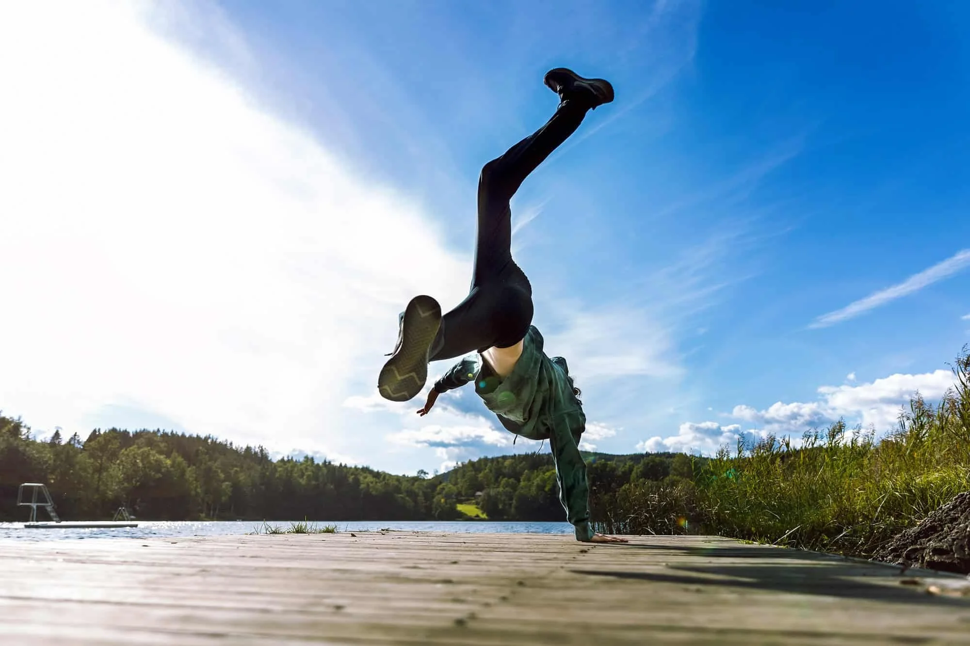 Konfirmant i hverdagsklær danser breakdance på ei trebrygge