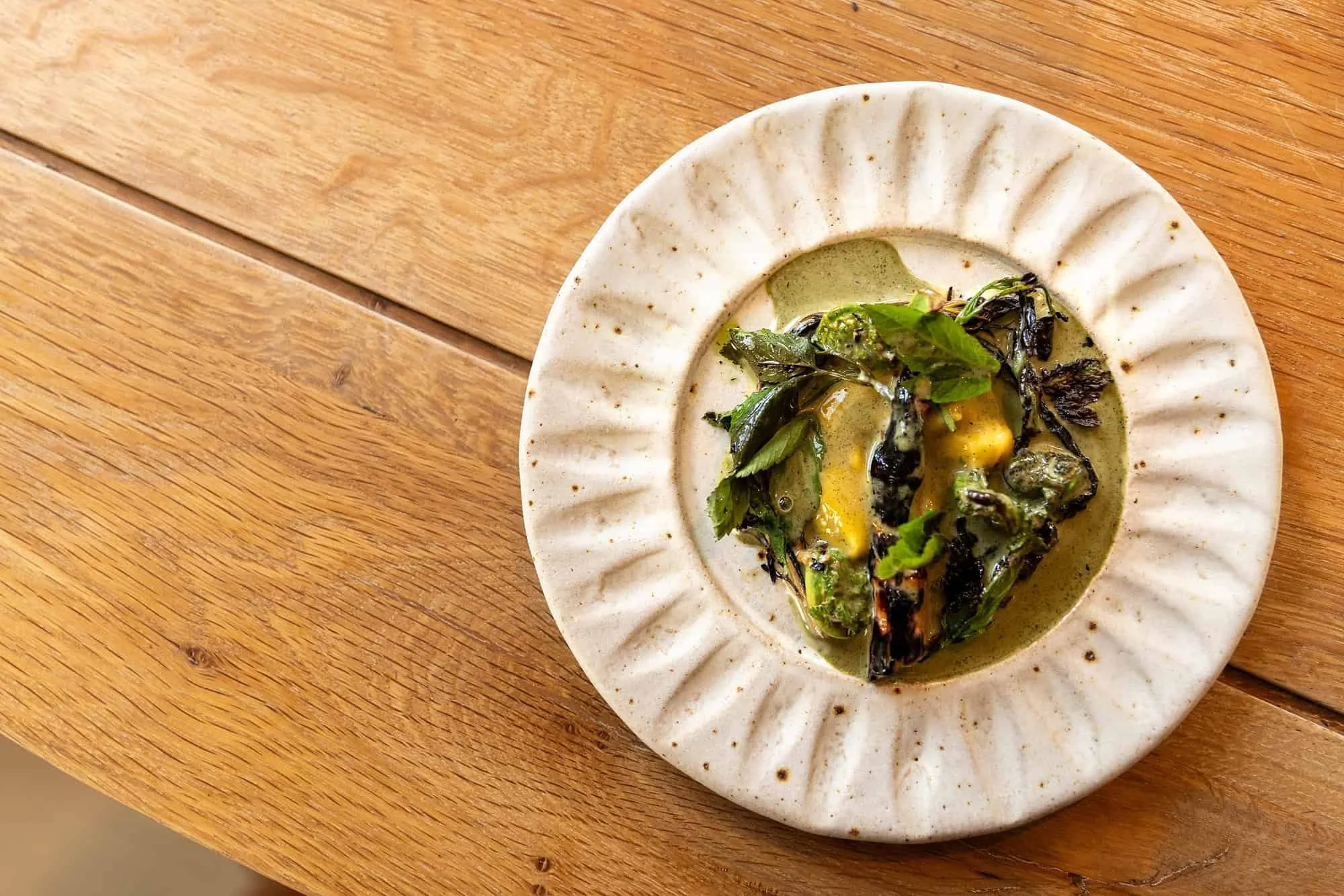 Hvit keramikktallerken med en salat lagd av ugress