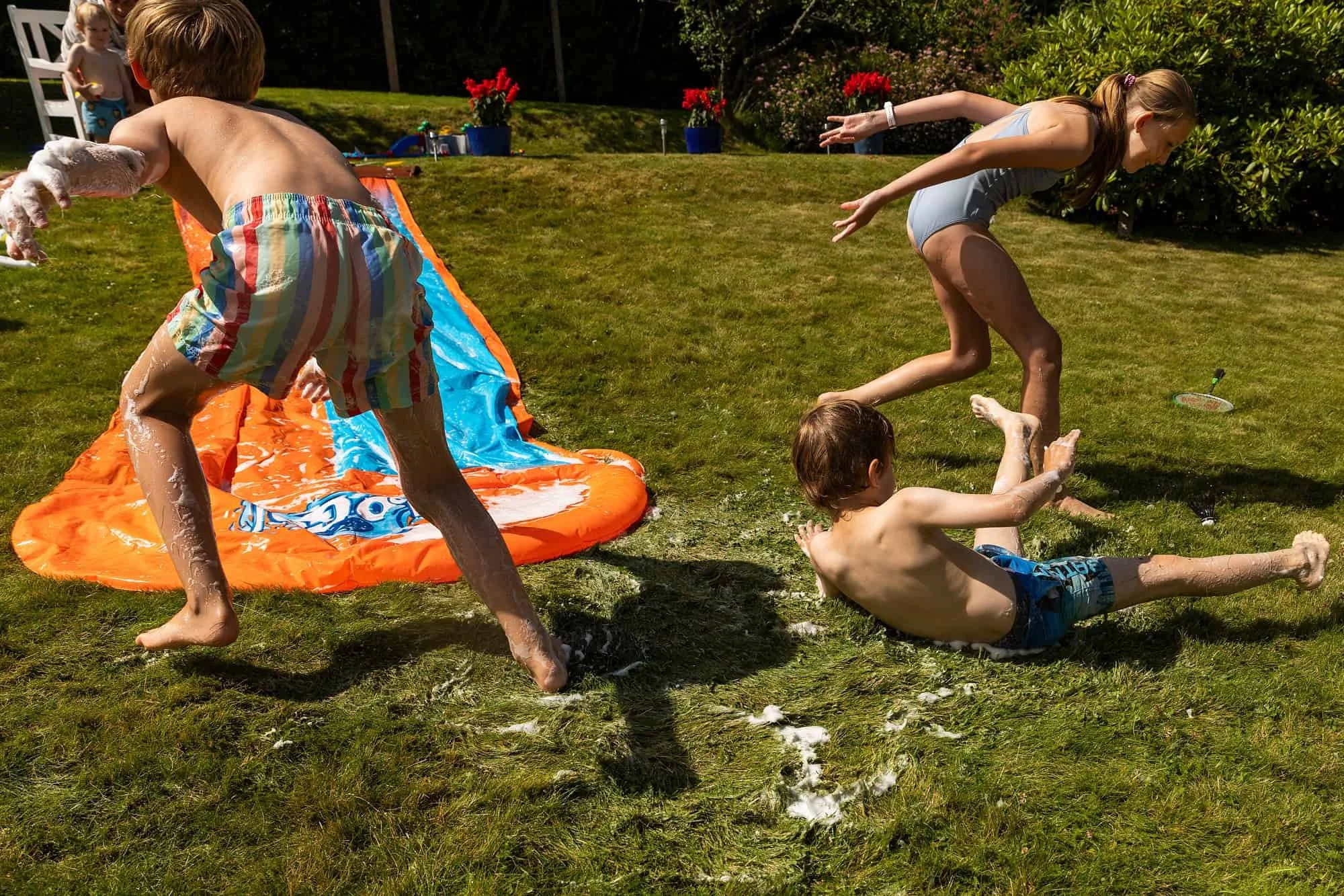 Barn leker på vannsklie i hagen under en varm sommerdag