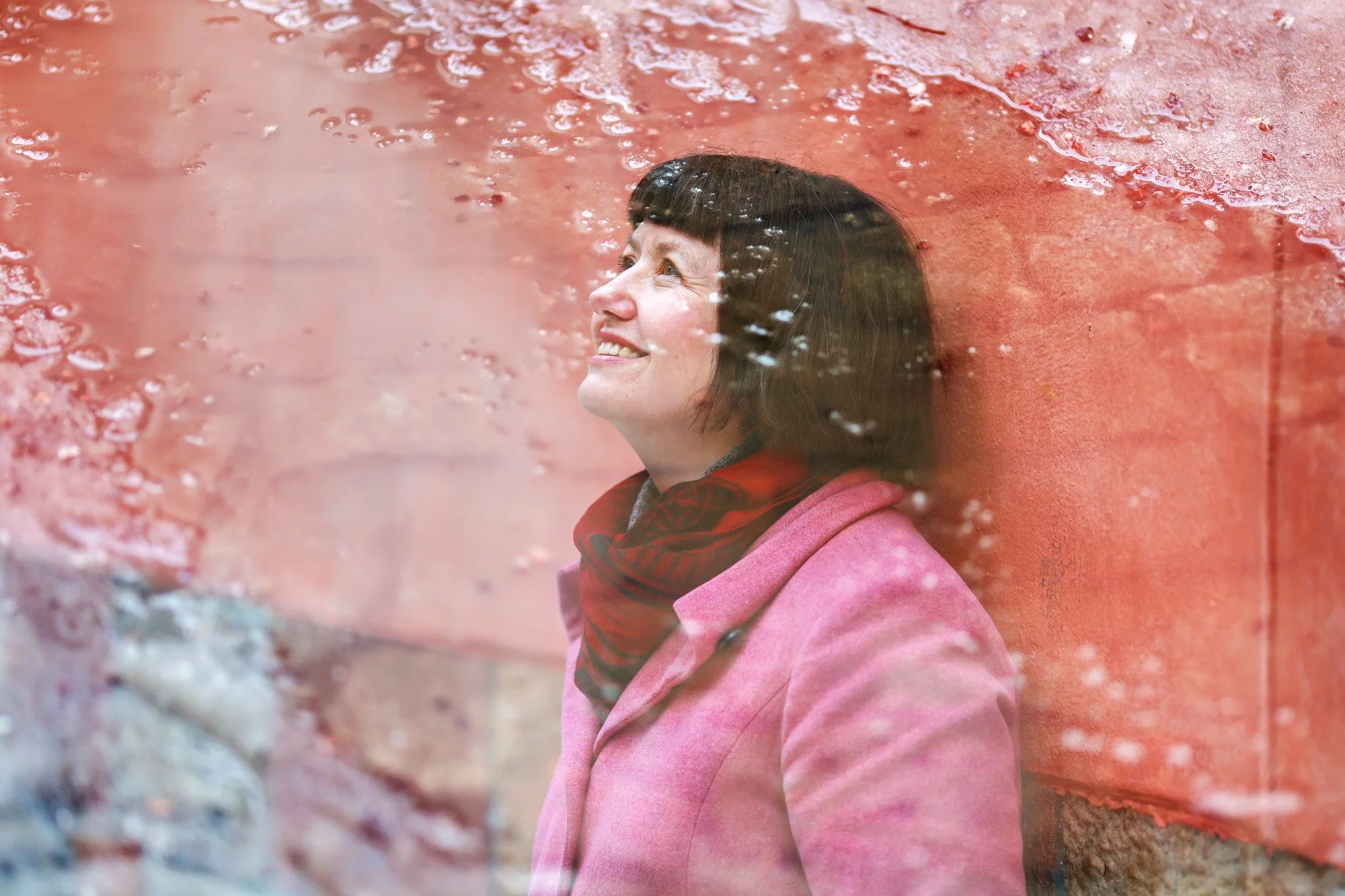 Smilende kvinne i rosa jakke ser oppover