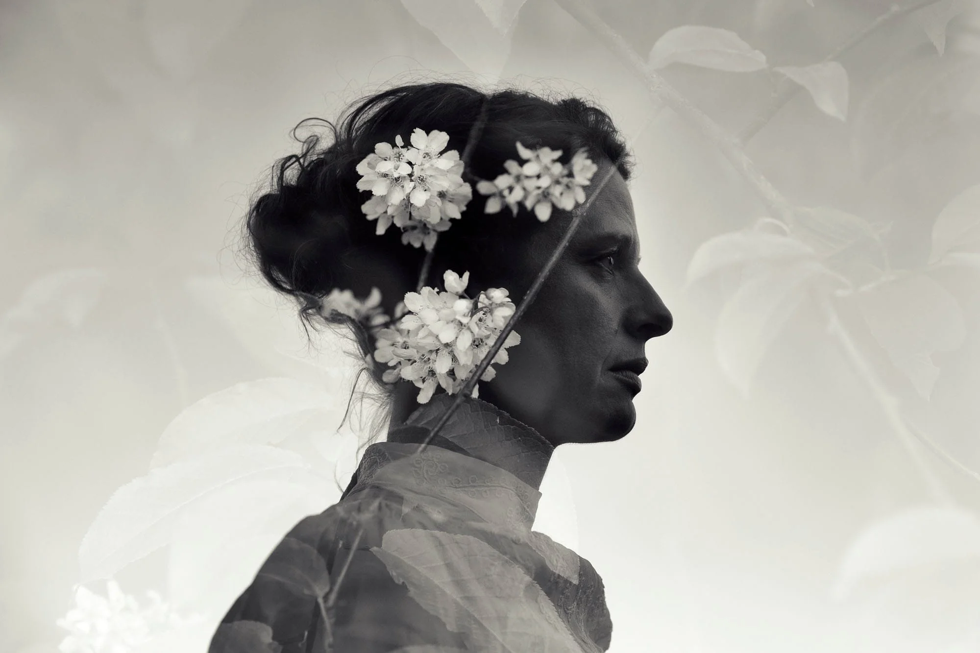 Dobbeleksponering av mørk profil av kvinne med hvite blomster i håret