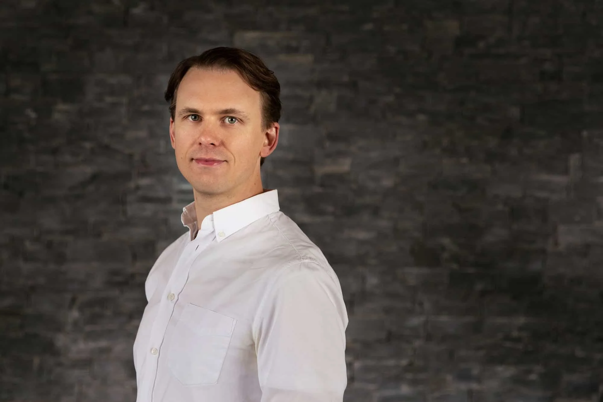 Lege i hvit skjorte mot mørk myúrvegg
