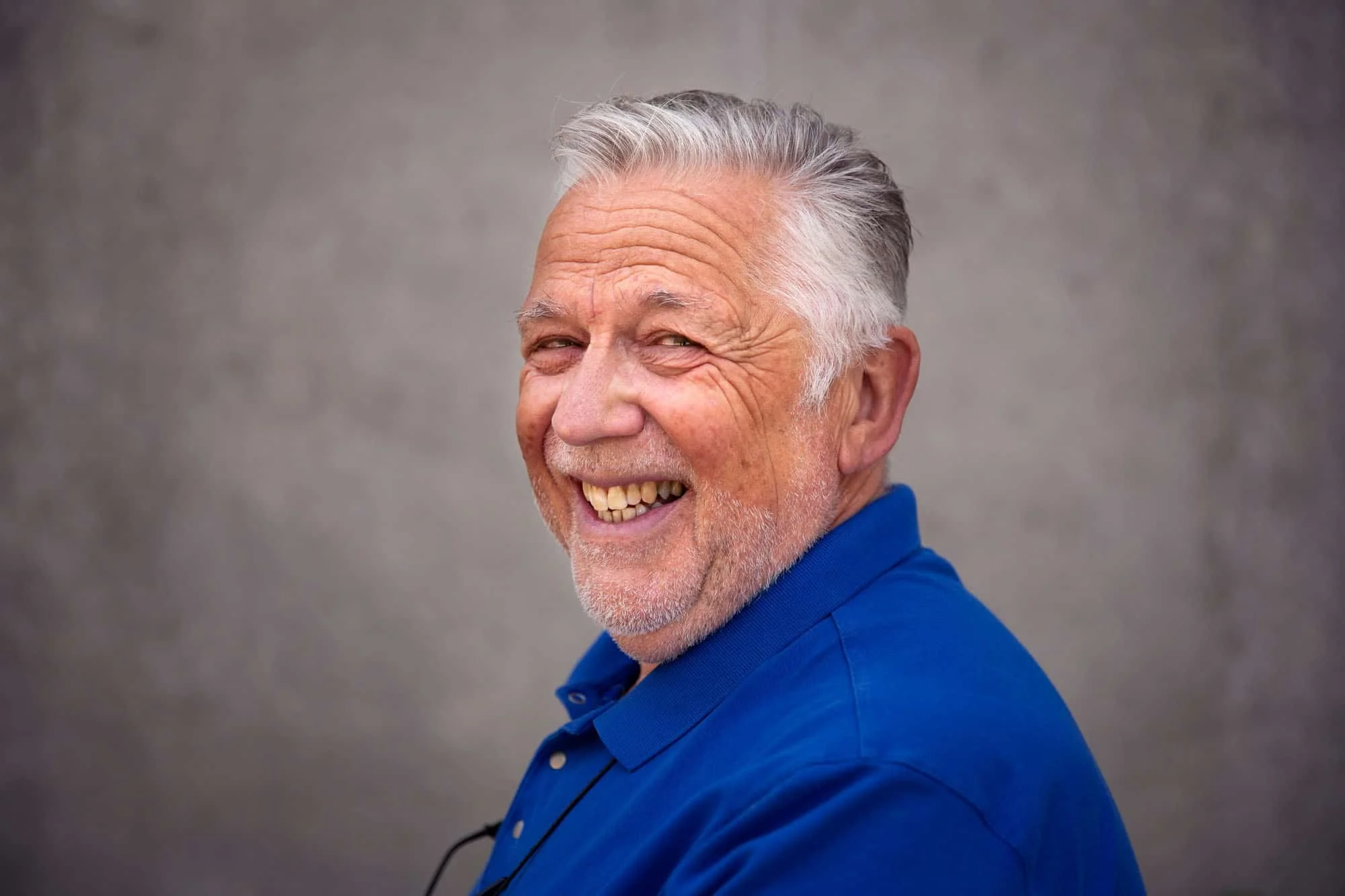 Smilende eldre herre i knallblå trøye