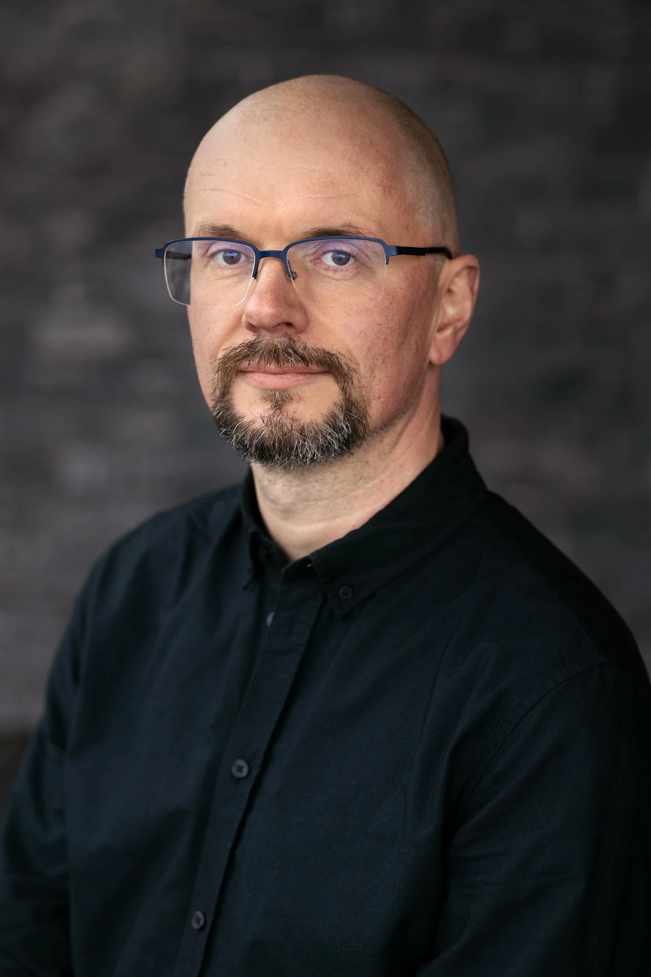 Alvorlig mann med skjegg og briller med sort skjorte