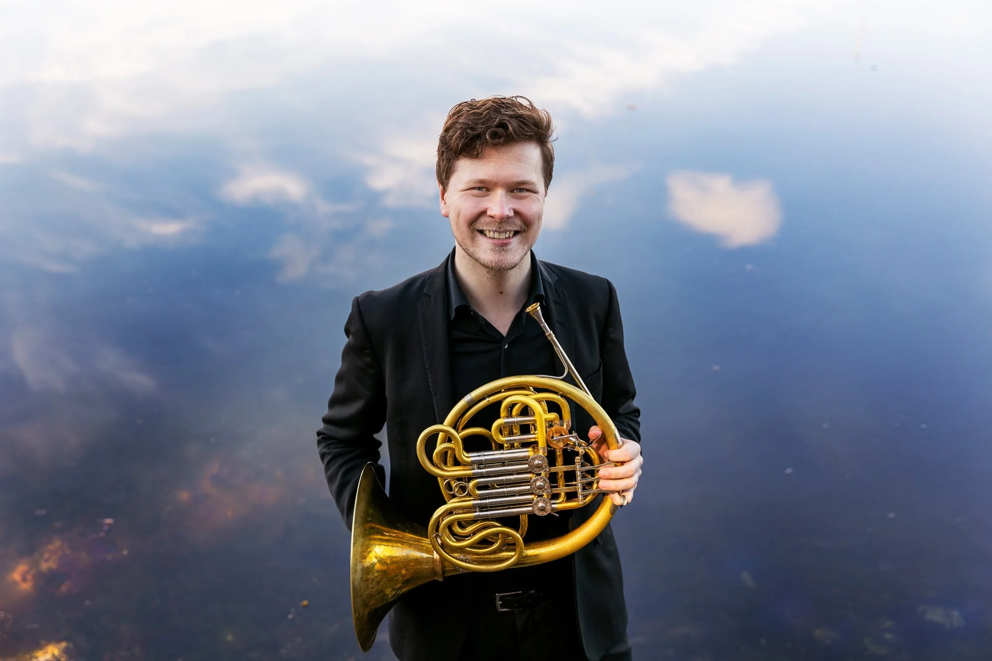 Portrettfotografering av hornist med speiling av himmel som bakgrunn