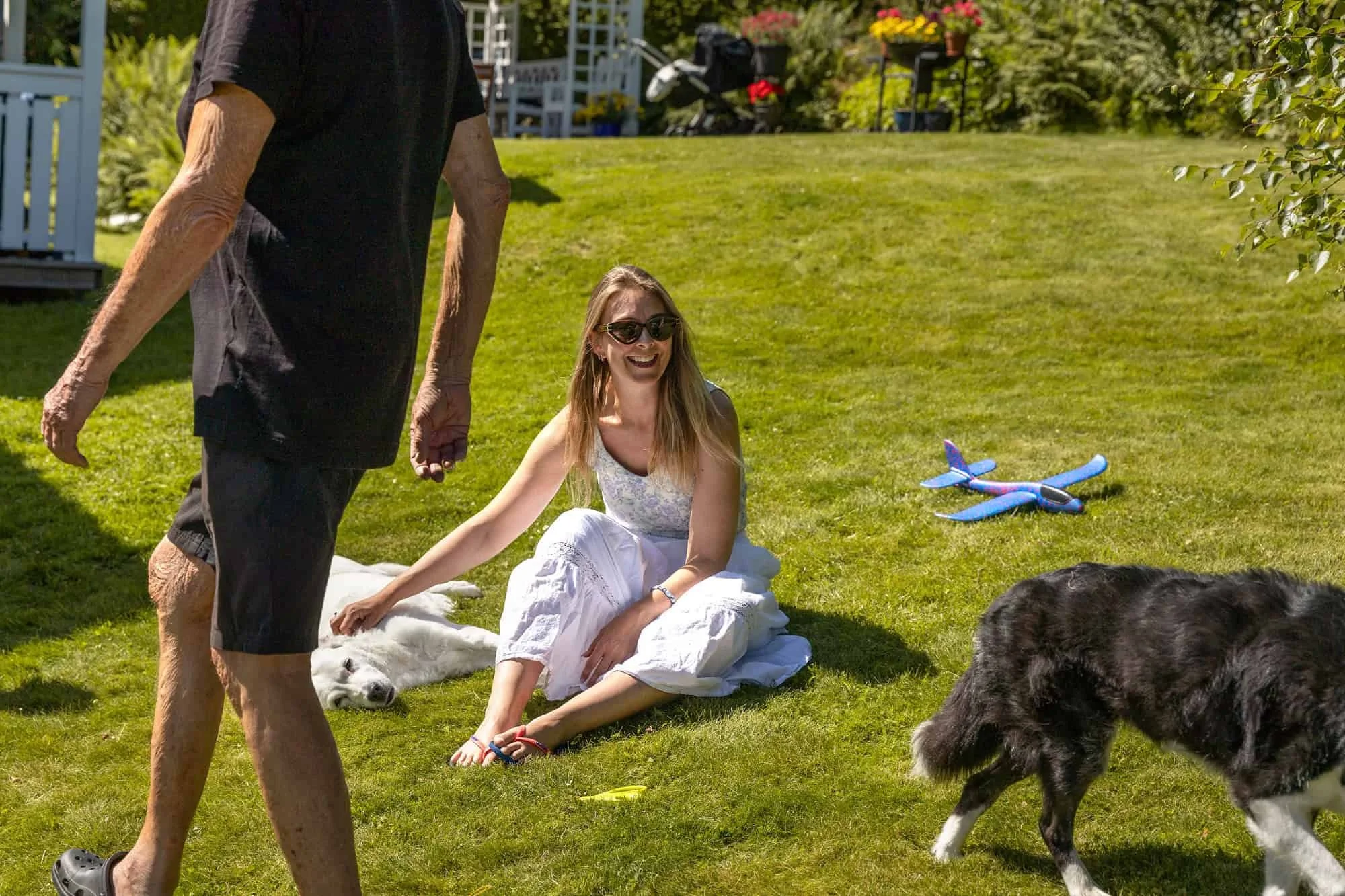 Kvinne sitter på plenen mens hundene slapper av rundt familien