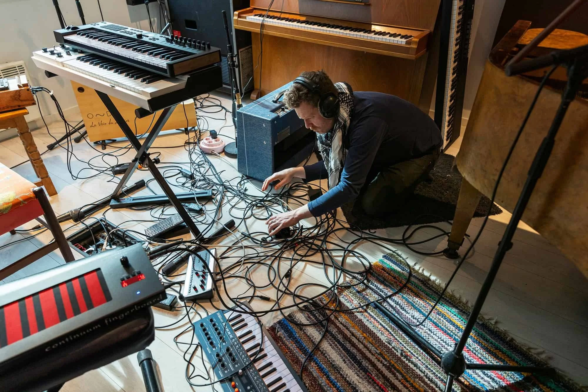 Musiker sitter på gulvet blant kabler og synther under innspilling i musikkstudio