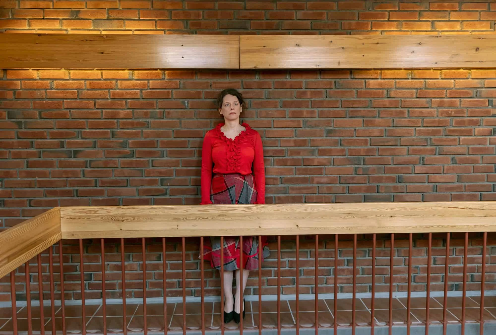 Skuespiller står foran murvegg og rekkverk i kreativt portrett på Oppsal Samfunnshus.