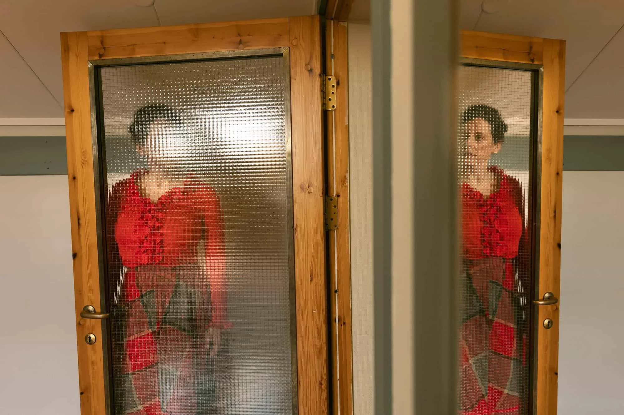 Kreativt portrett av skuespiller sett gjennom glassdører med speiling inne på Oppsal Samfunnshus.