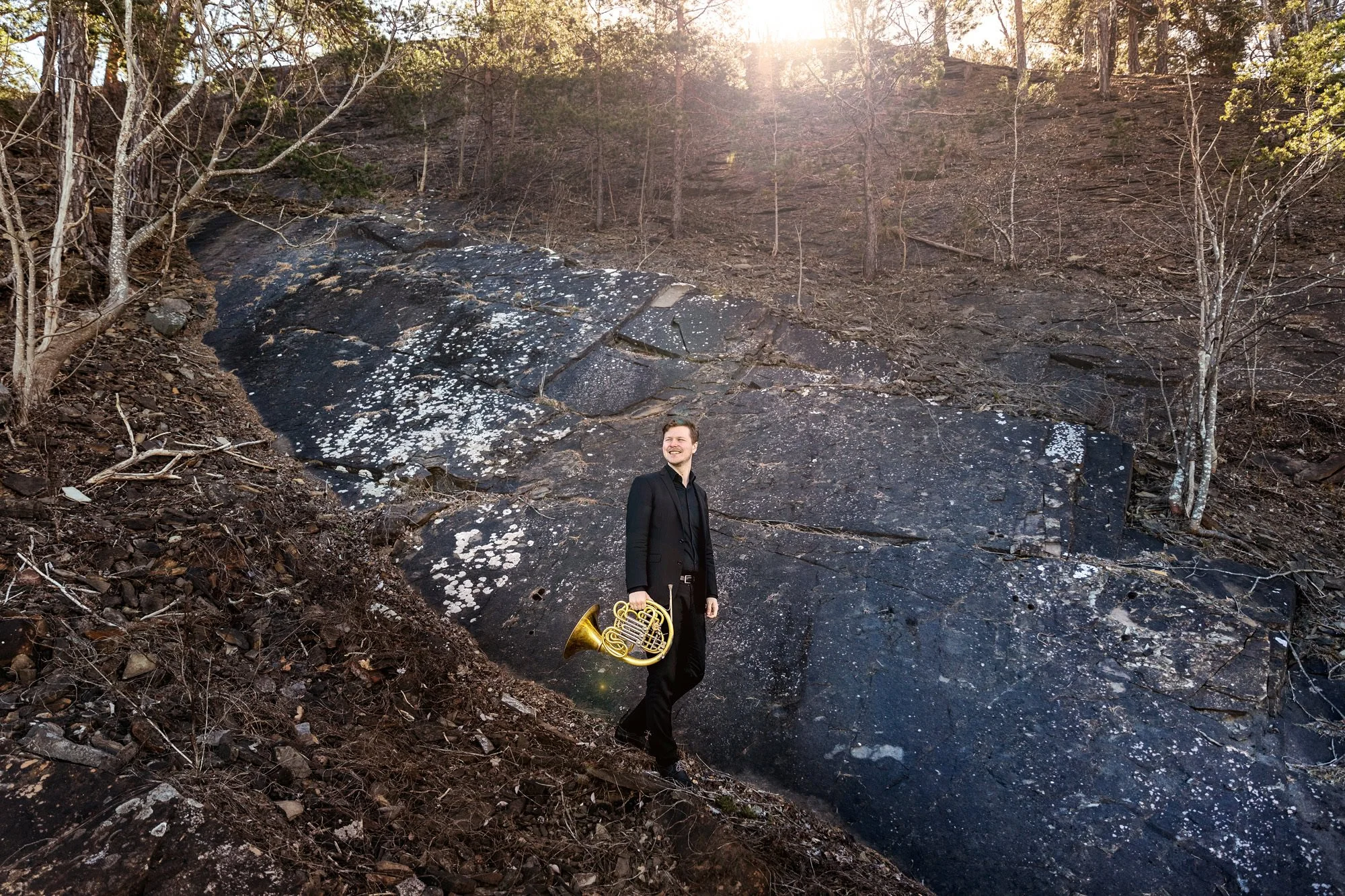 Hornist Simen Hagen går nedover fjellsiden på Gressholmen, fotografert ute på location i Oslofjorden.