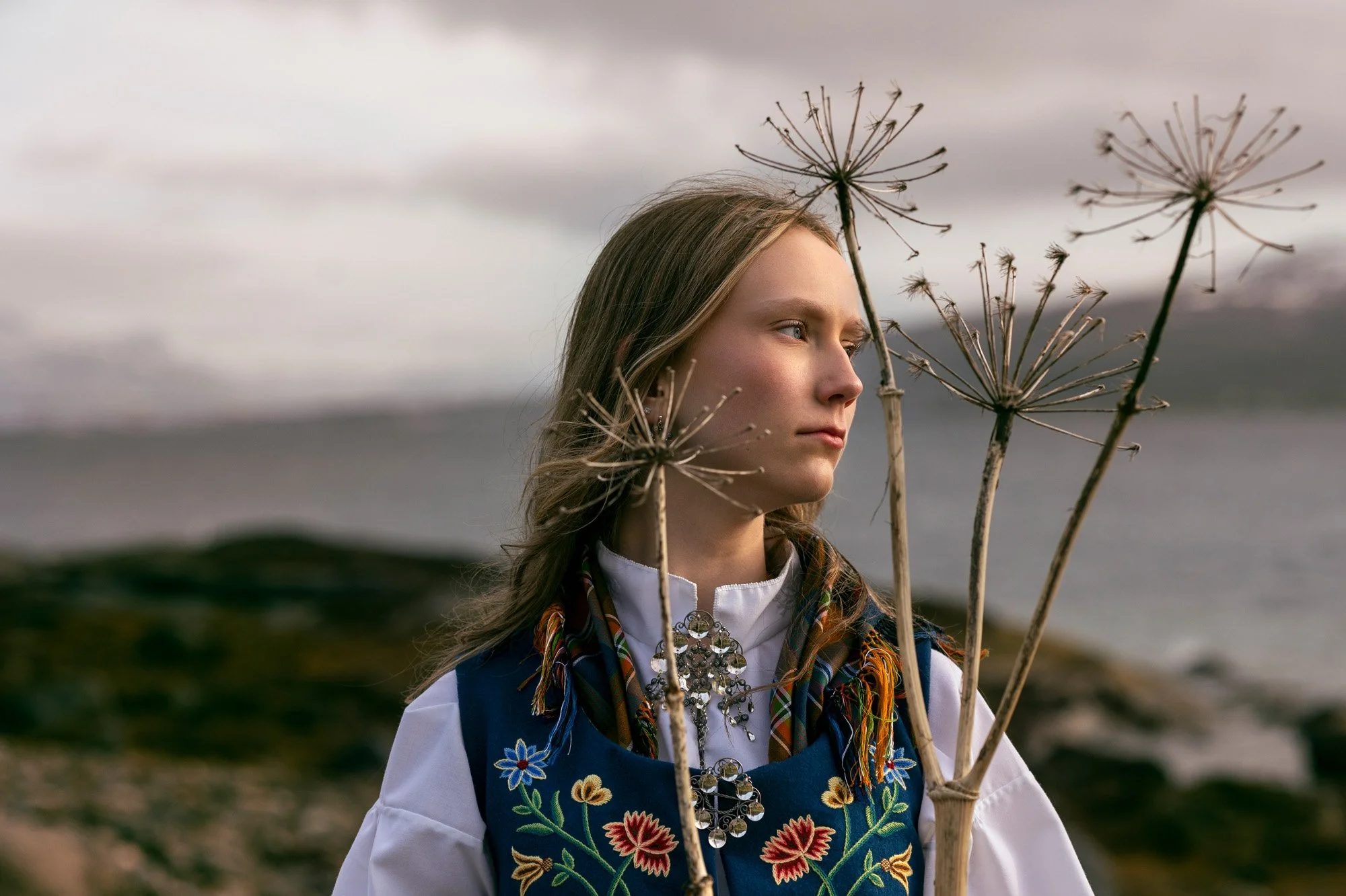 Konfirmant i blå Nordlansbunad poserer med fire Tromsøpalmer