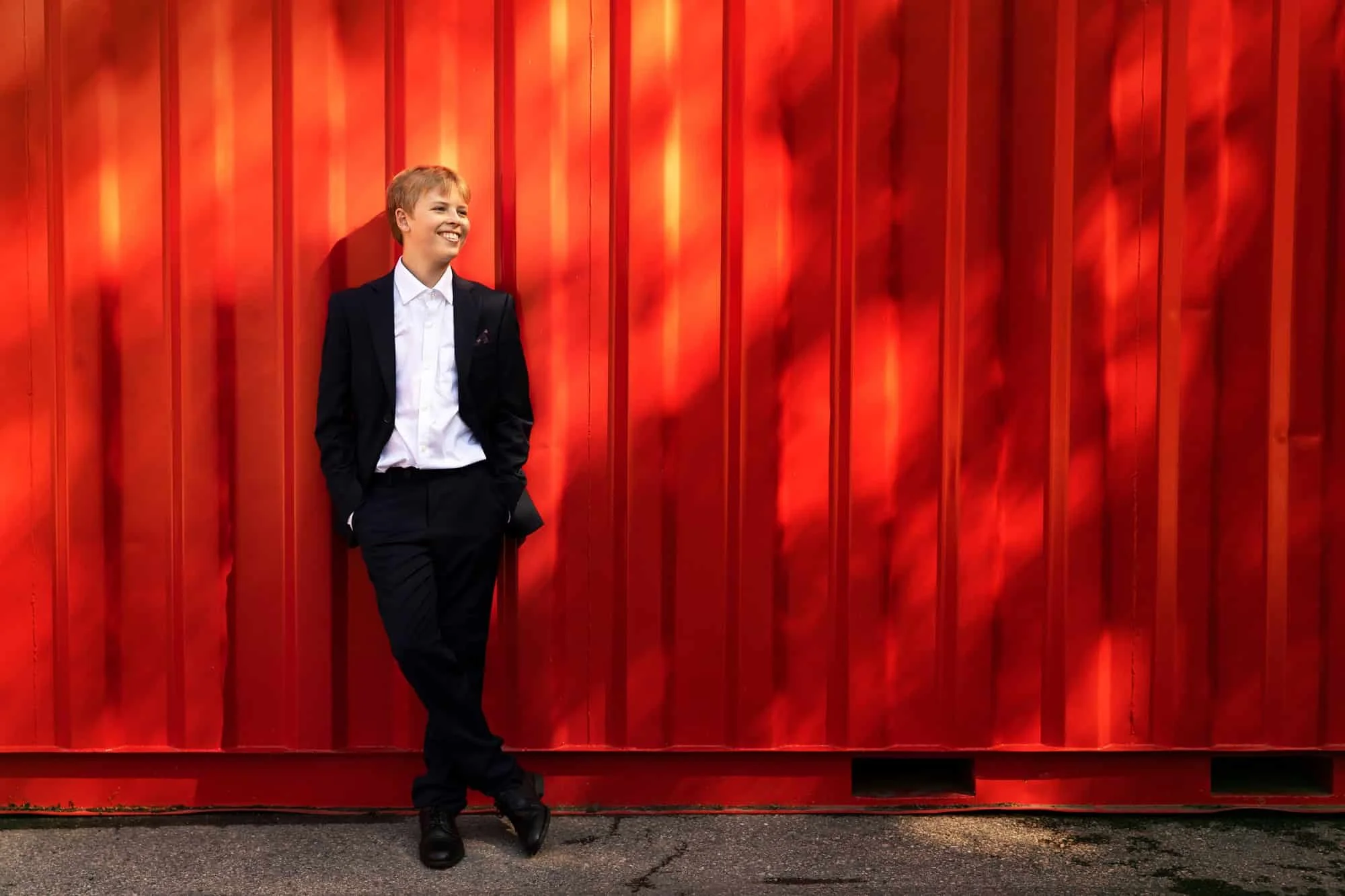 Konfirmant i dress fotografert mot containervegg i urbane omgivelser i Oslo