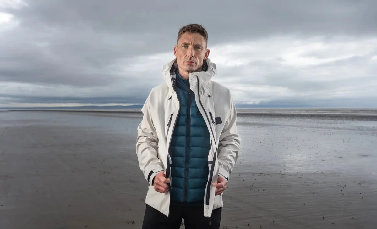 British male model Matt Sharman wears a white waterproof jacket and green padded jacket made by Shackleton in a lifestyle shoot in South-West England