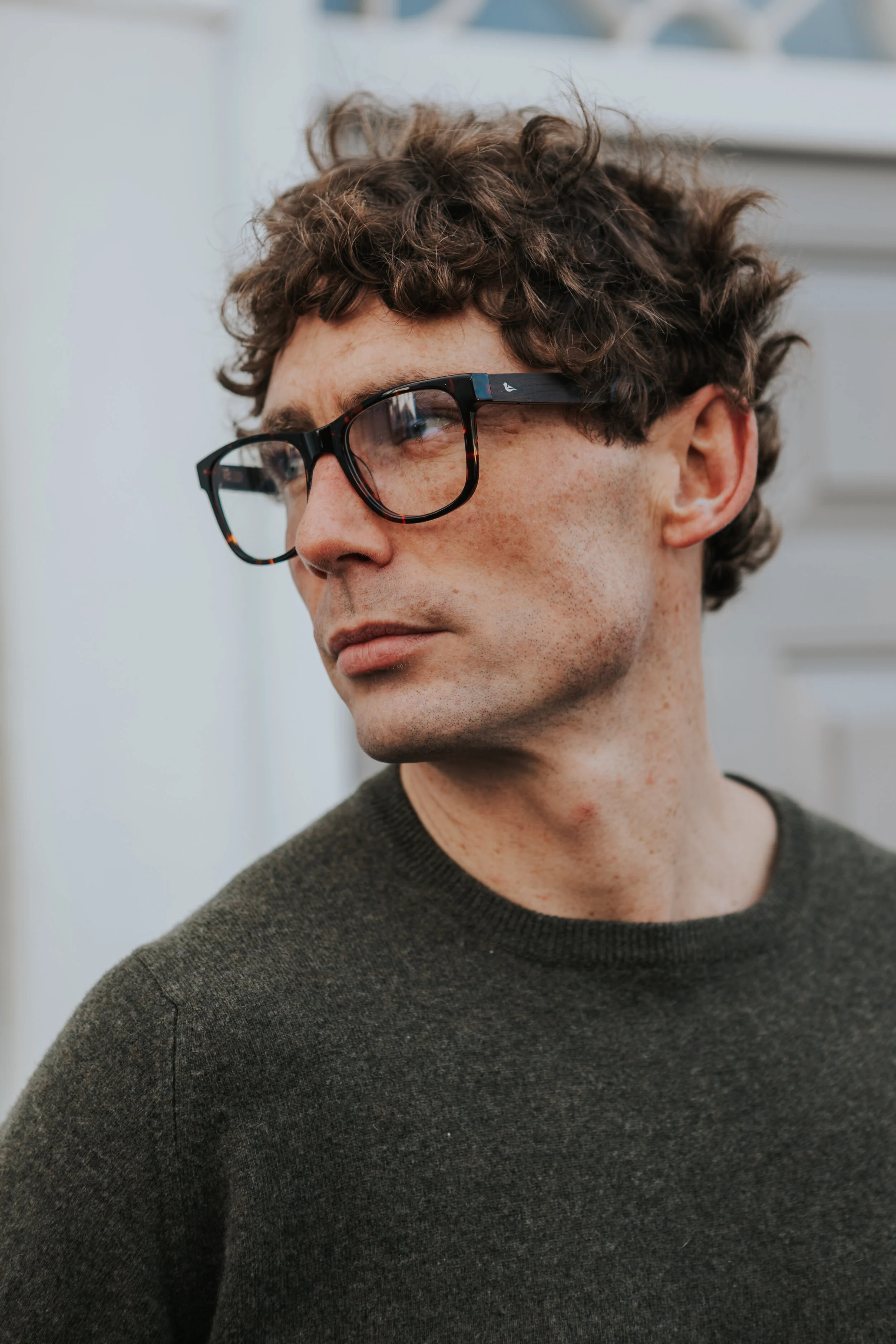 Male model Matt Sharman wears Bird Sunglasses and a green jumper