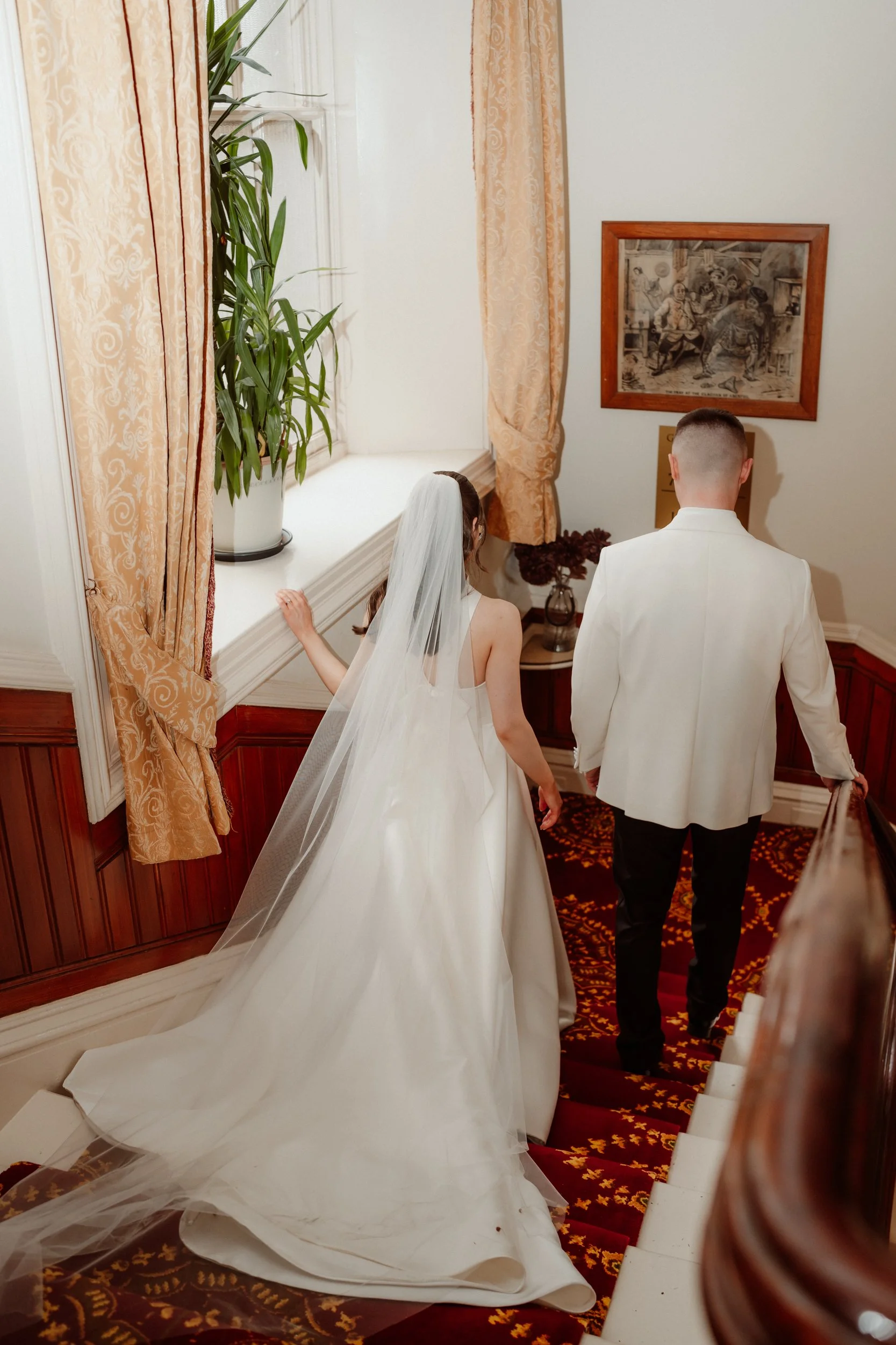  Bride and groom walking down staircase  together inside Atholl Palace Hotel during their intimate wedding. 