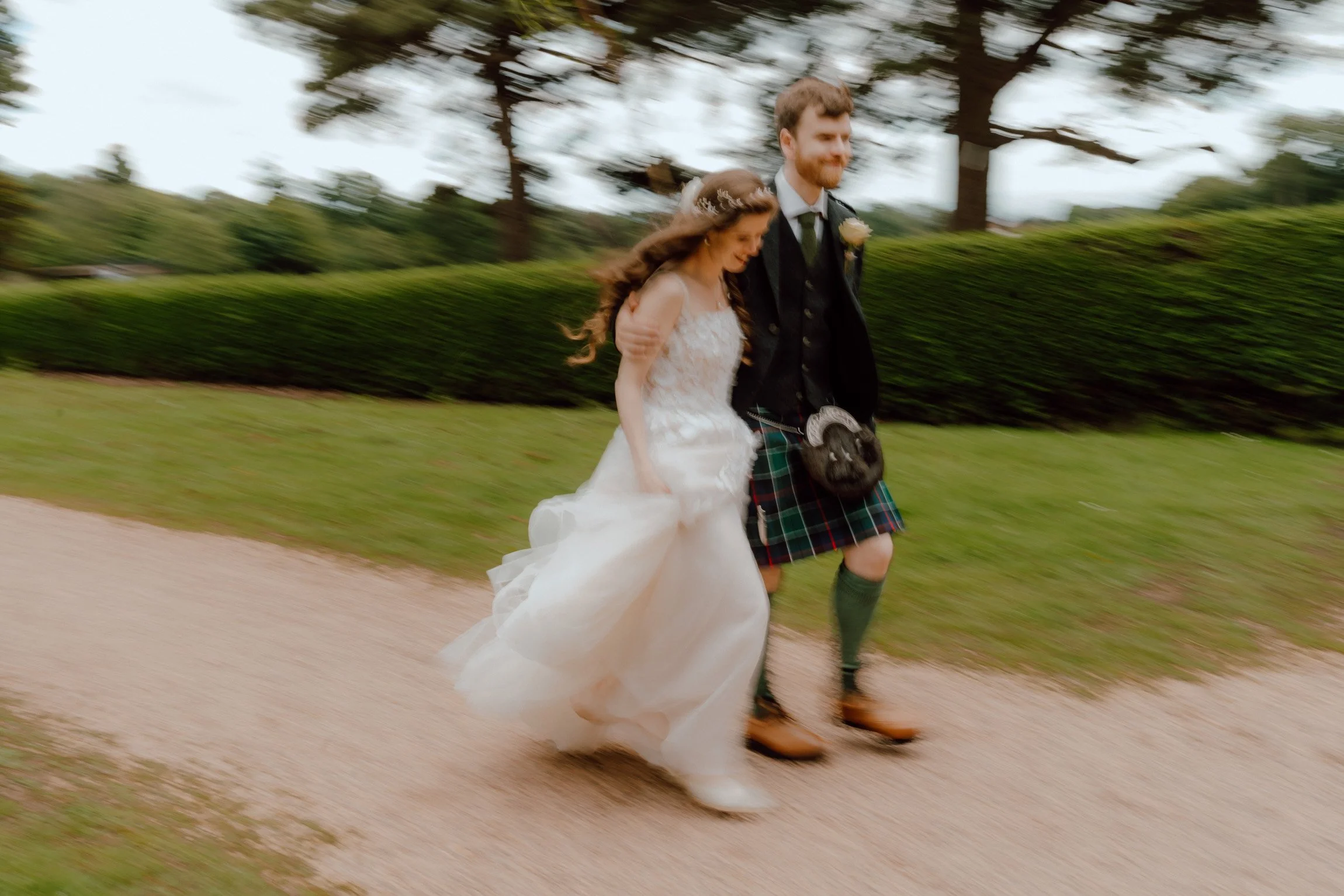   Bride and groom embracing in the gardens outside Oswald House during relaxed documentary wedding portraits.  