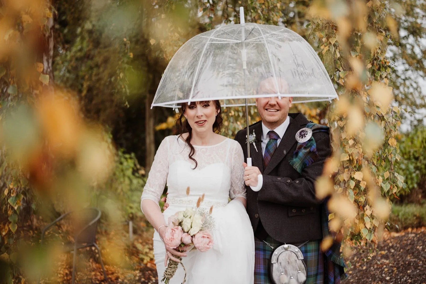 Bride and groom embracing the Scottish rain during their Megginch Castle wedding photographs