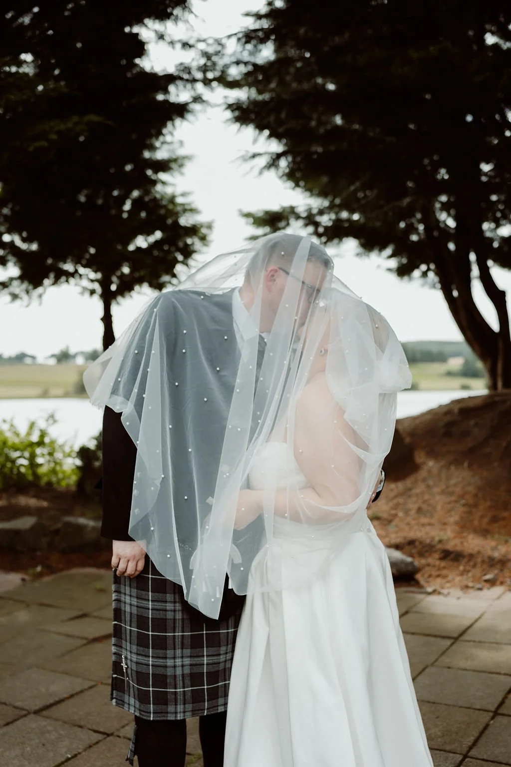 Ryan and Ashleigh sharing their first kiss beneath draped fabric during their Piperdam ceremony