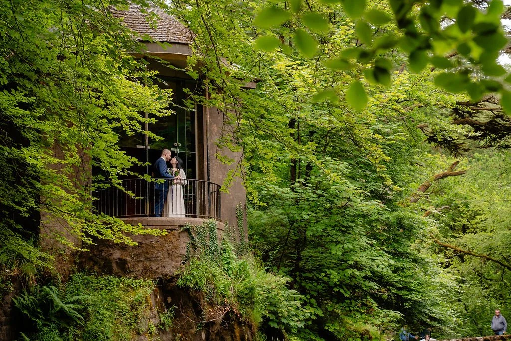 Couple embracing during their elopement at The Hermitage, Scotland, surrounded by lush woodland and the iconic Ossian's Hall.
