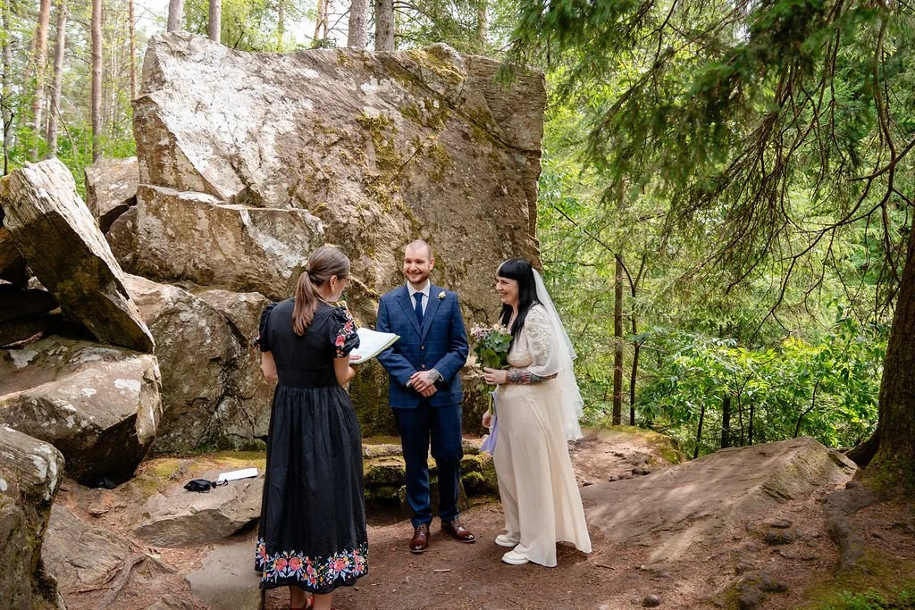 Couple saying their vows during a woodland elopement at The Hermitage in Perthshire, Scotland, beside the iconic Ossian's Hall boulders.
