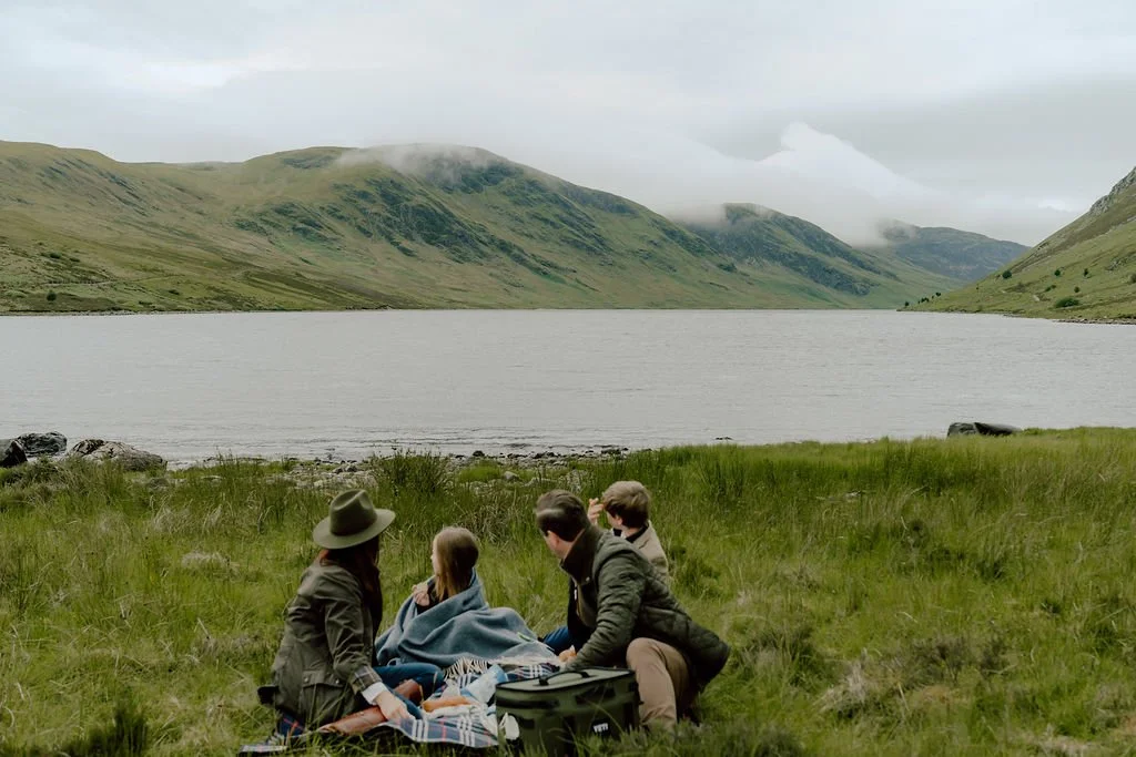 Family relaxing together beside a Scottish loch turret during their Gleneagles family photography experience photographed by Patrice Little Photography