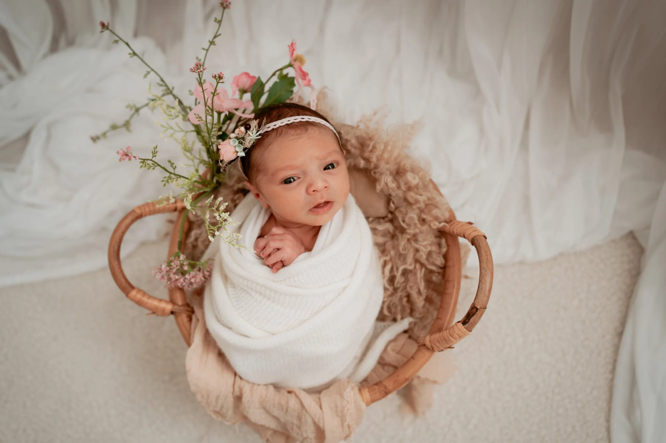 Baby curled up in a basket in wrapped position.