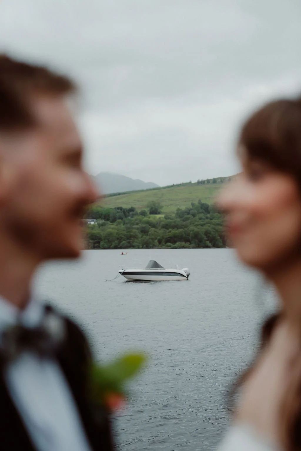 Creative close-up portrait of a newlywed couple with a Scottish loch and mountains visible between them photographed by Patrice Little Photography.