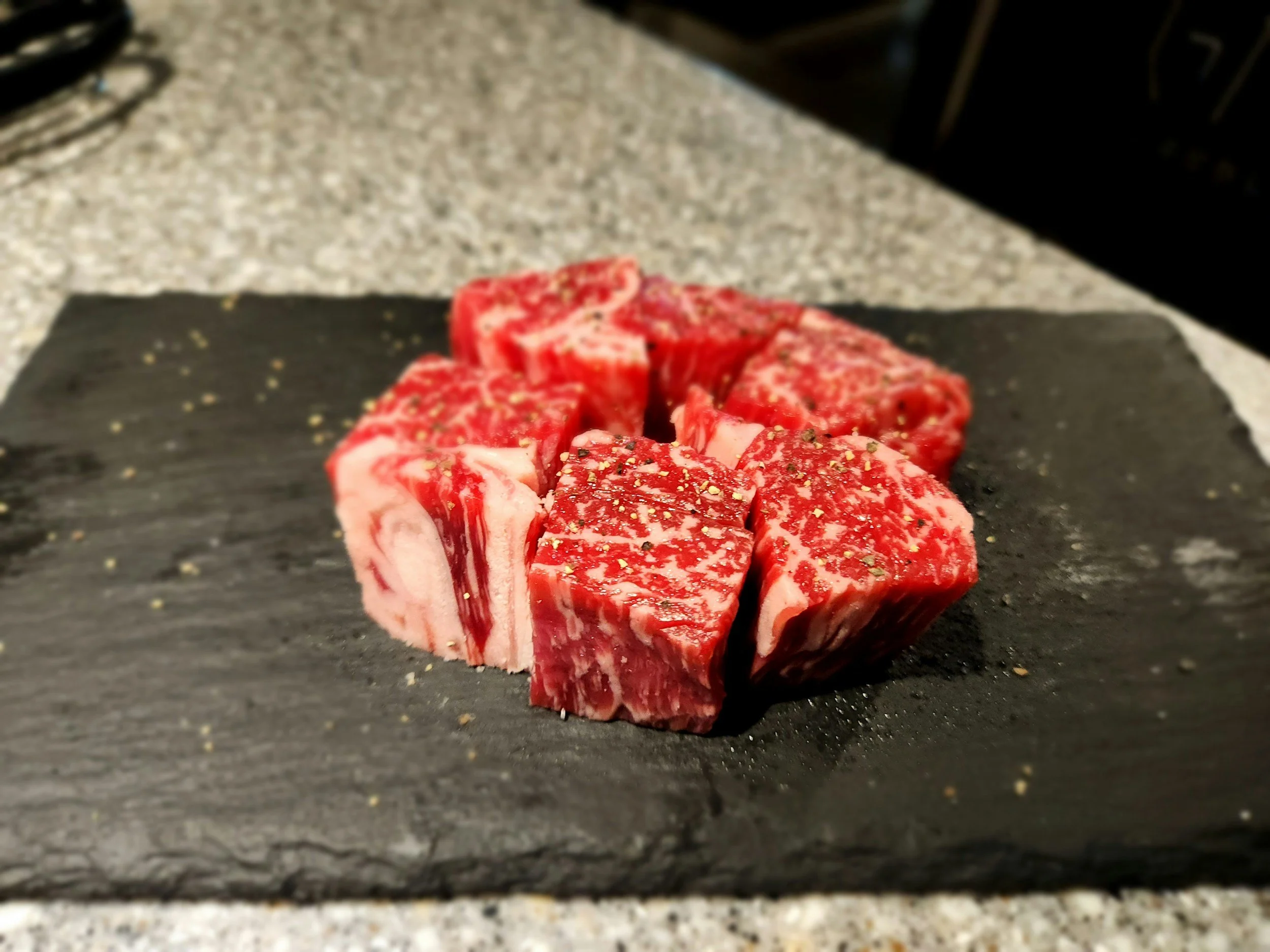 Chunks of raw beef on a slate cutting board