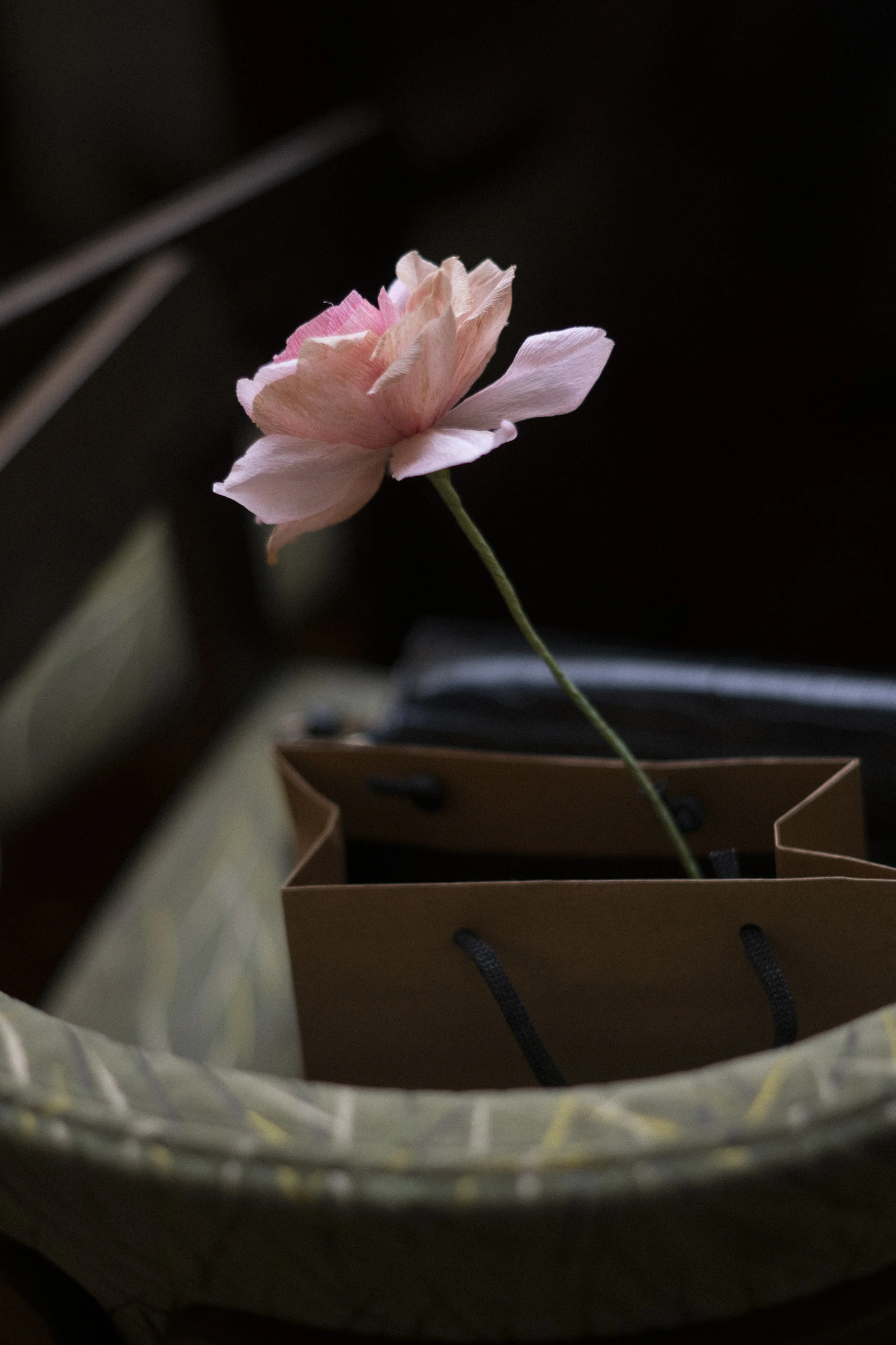Pink paper rose in a brown paper bag placed on a chair
