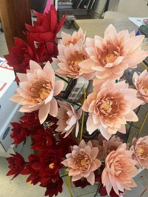 Artificial peach and red lotus flowers by Emmeli Kimhi in a floral arrangement on a table.