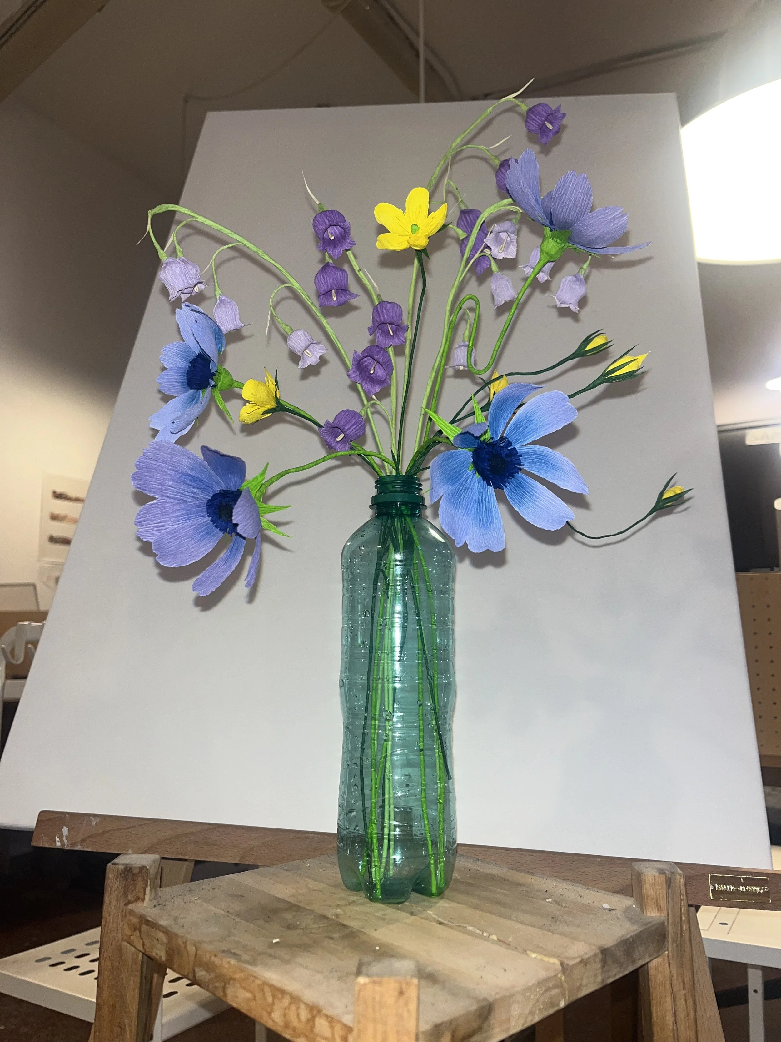 Artificial paper flower bouquet  by Emmeli Kimhi in a green glass vase on a wooden table