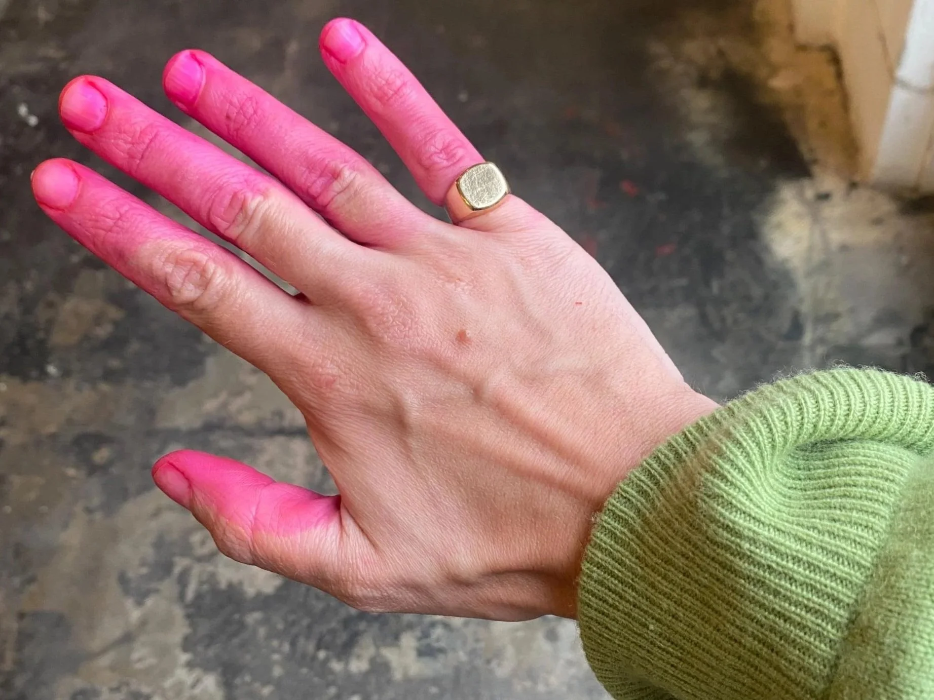 Hand with bright pink dye on the fingers after dyeing paper, wearing a gold ring – behind the scenes in Emmeli Kimhi’s studio