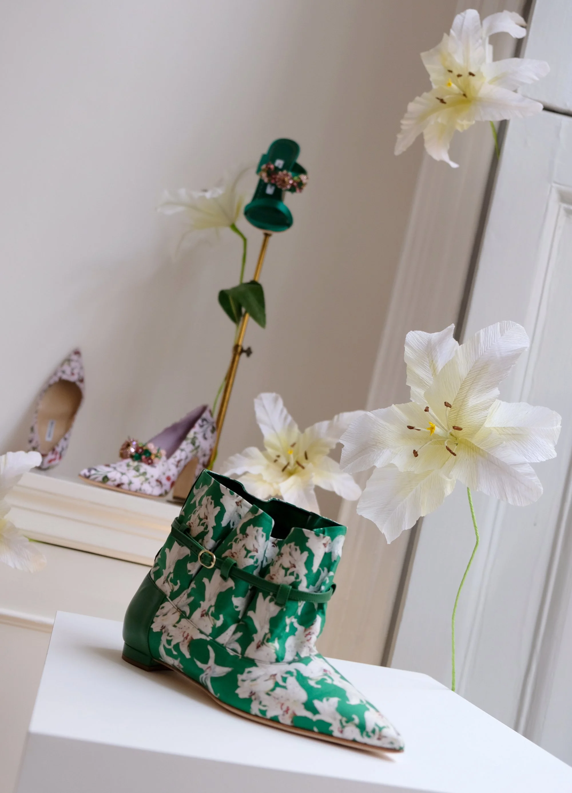 White paper lilies by Emmeli Kimhi styled with a green floral print boot and decorative accessories