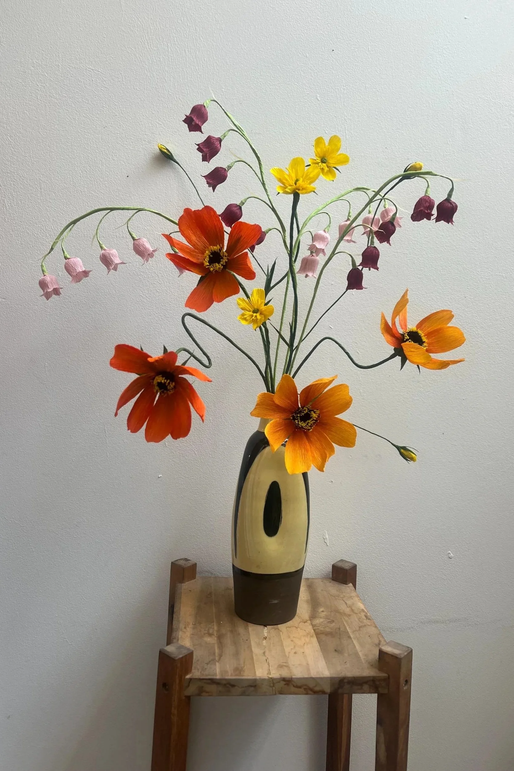 Large handmade wildflower meadow bouquet featuring orange cosmos, yellow wildflowers and purple-pink bells in a ceramic vase, sculptural paper flowers by Emmeli Kimhi