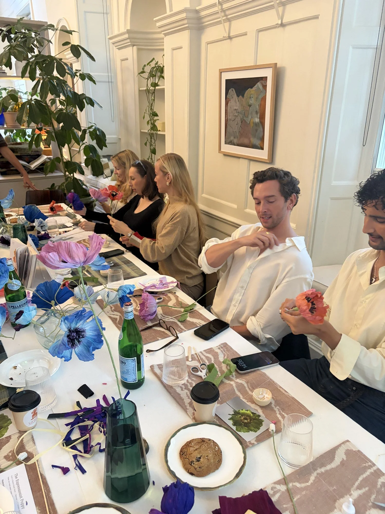 Guests shaping paper petals in the Sister showroom, with paintings on the wall behind