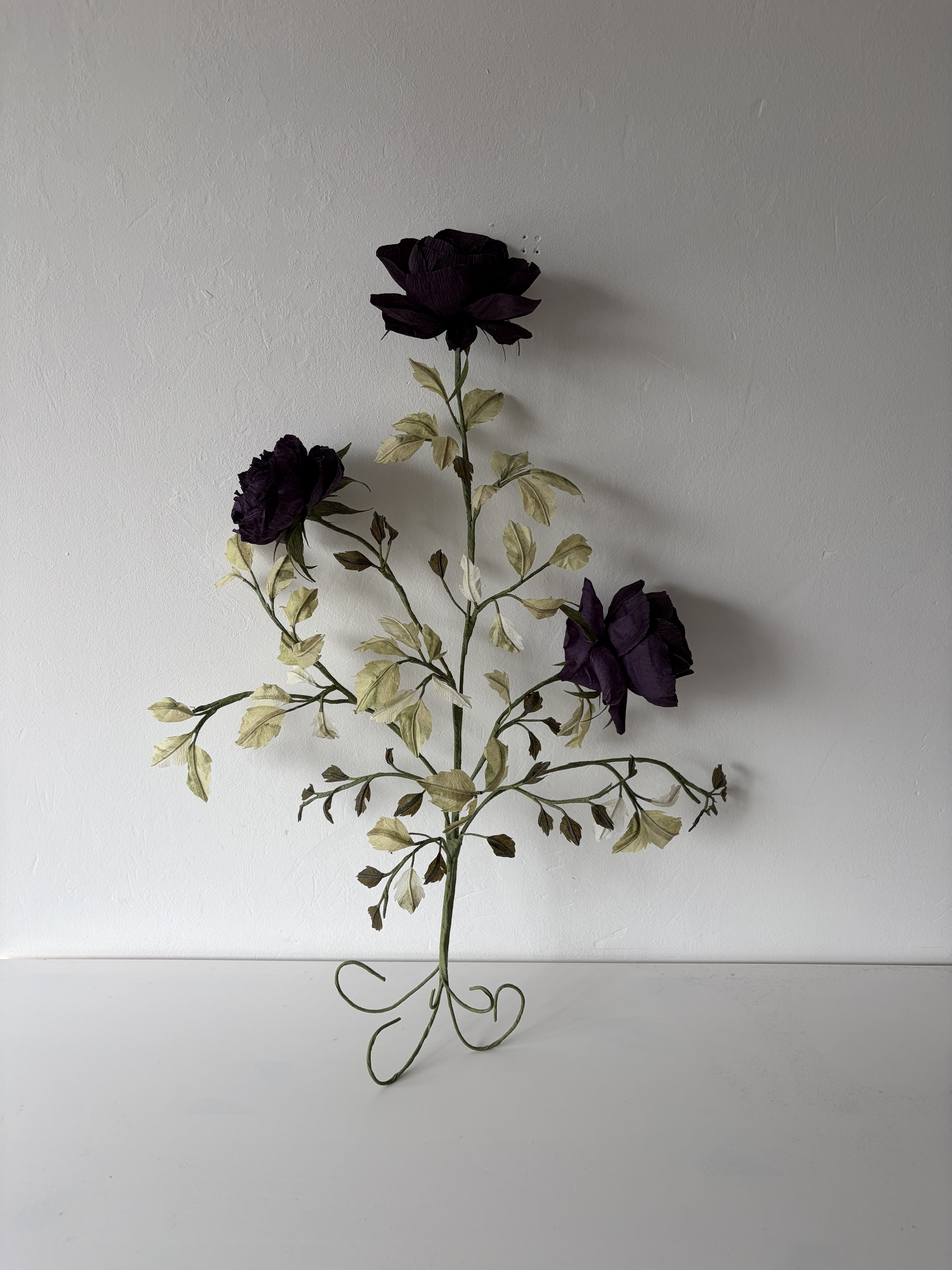 Handmade deep amethyst paper rose branch sculpture by Emmeli Kimhi, North London – three lush purple crepe paper roses with hand-painted pale green leaves on flexible wire stem