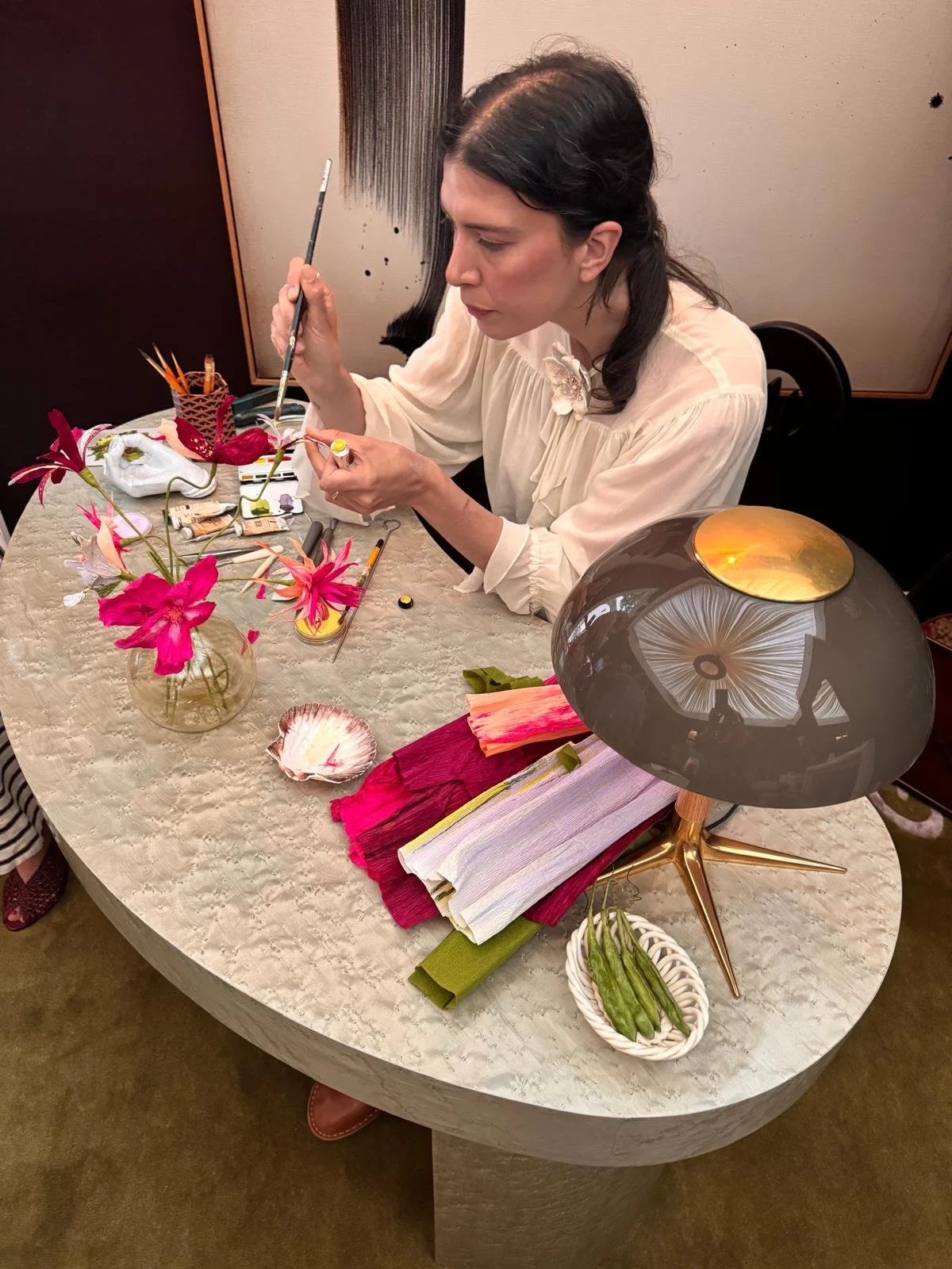 Emmeli Kimhi hand-painting a paper cosmos flower during her live demonstration for Studio Duggan at WOW!house 2026. Focused detail shot at the Holden Desk in The SpeakEasy Salon.