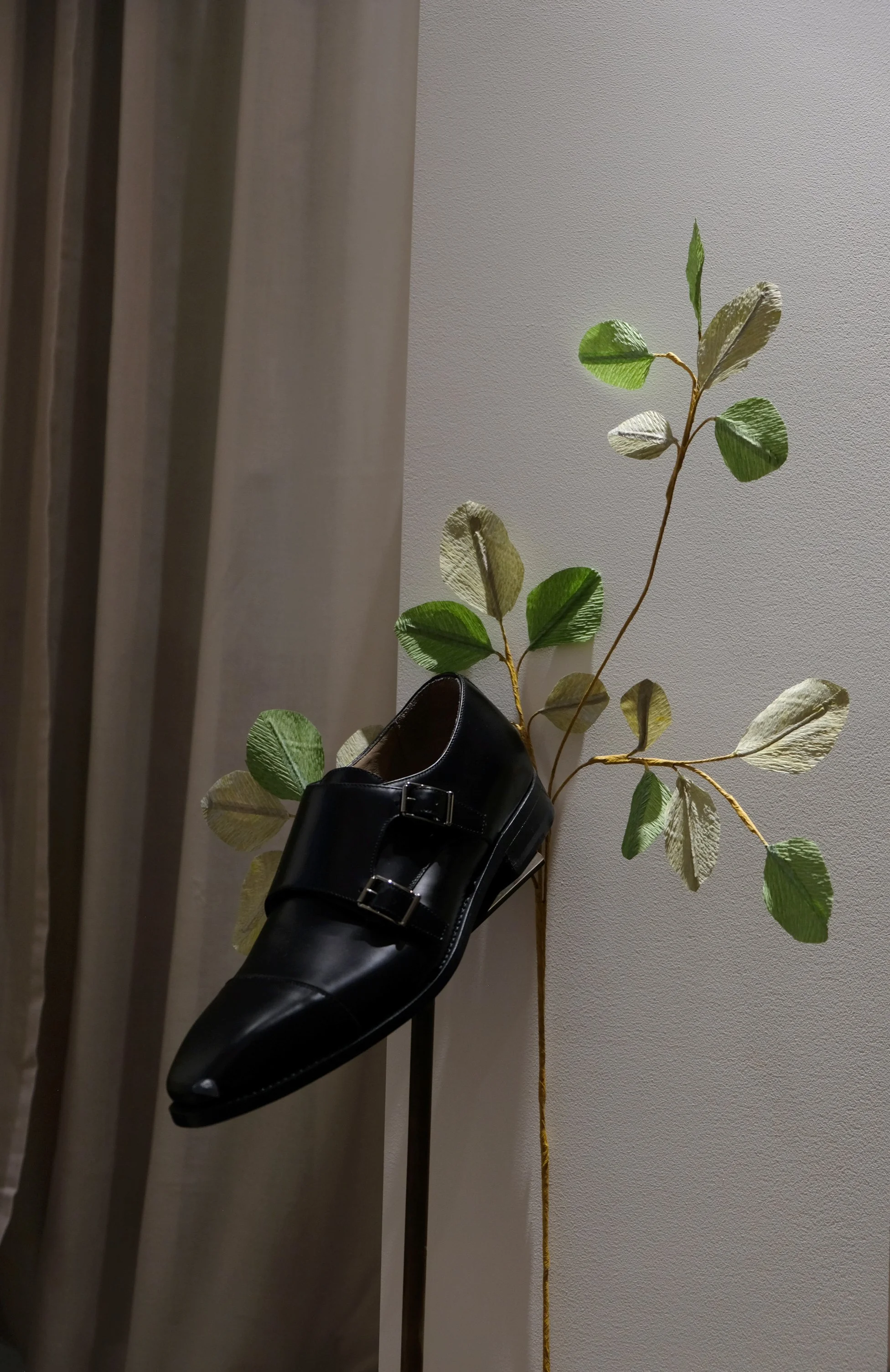 Green handcrafted paper foliage by Emmeli Kimhi styled with a black leather monk strap shoe