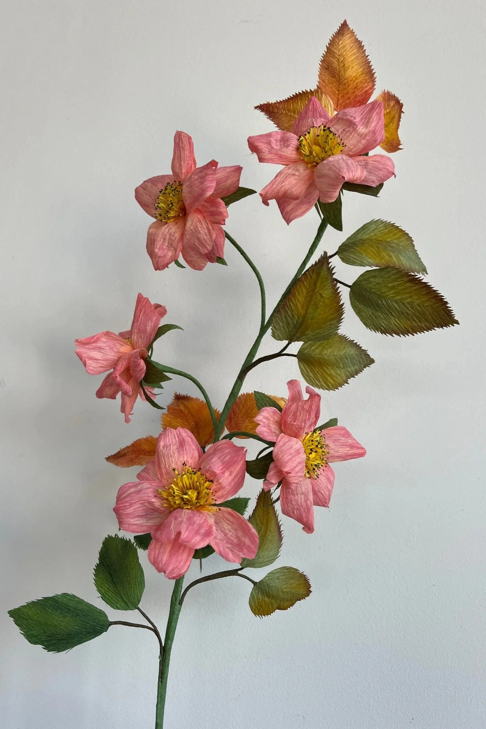 Detailed view of a sculptural handmade pink wild rose branch featuring multiple blooms and autumnal variegated foliage by Emmeli Kimhi