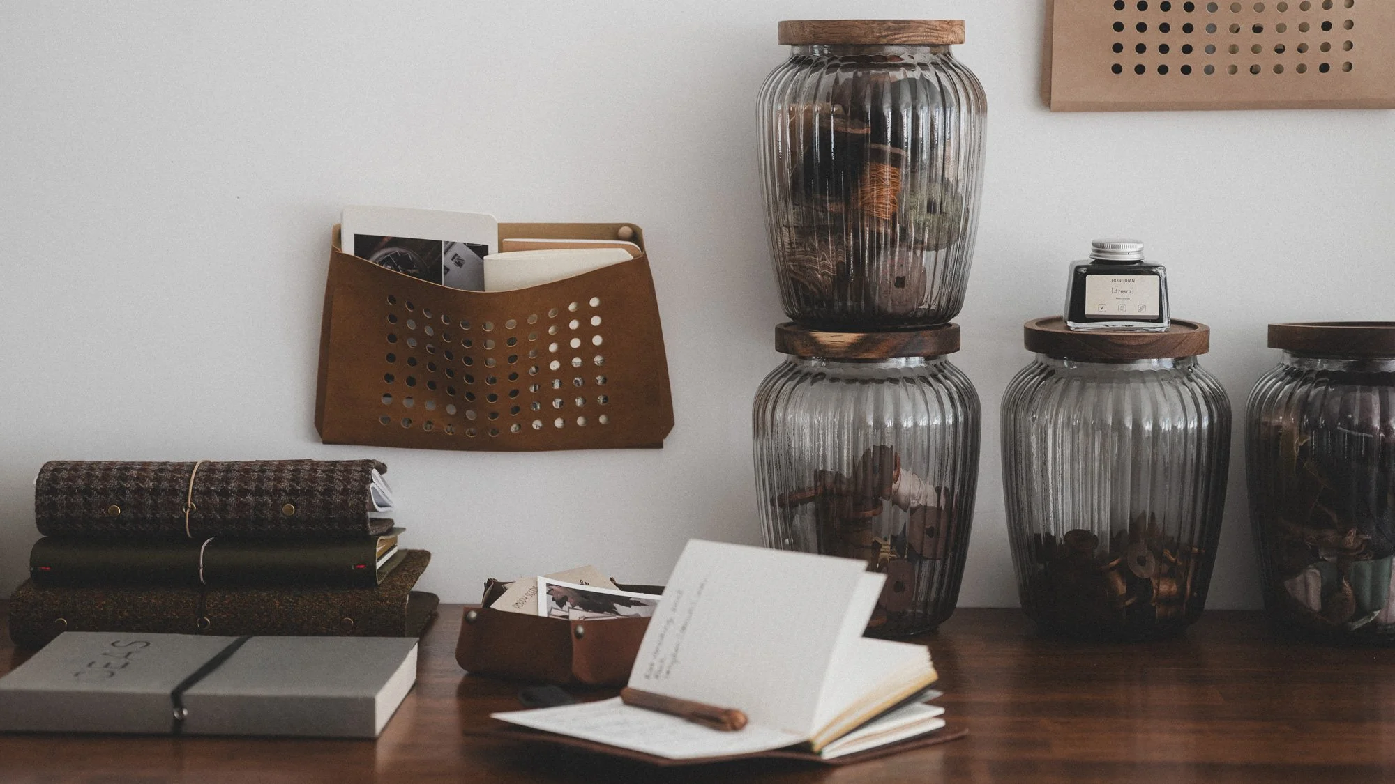 leather pouches on wall with stationery things on desk
