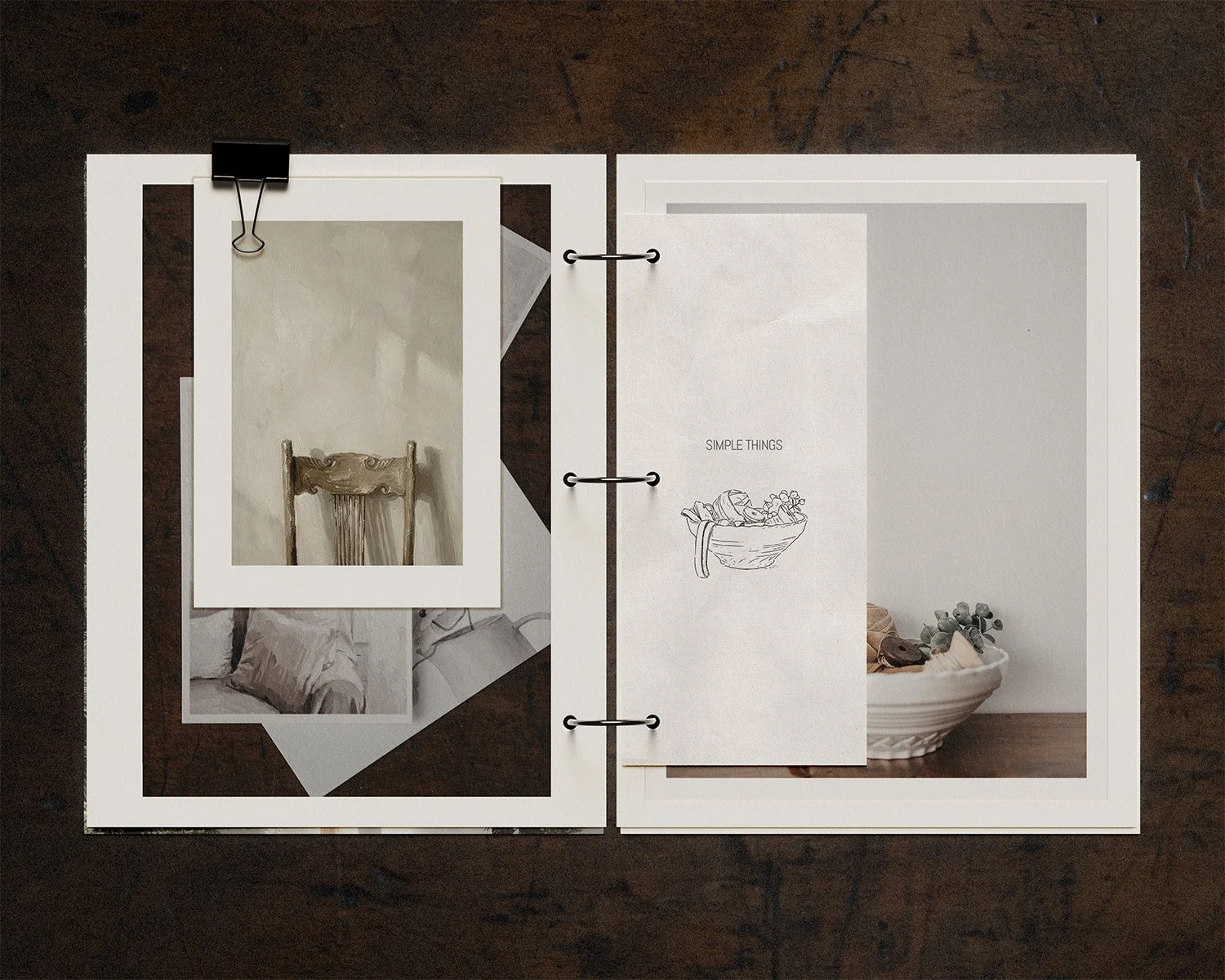 Open scrapbook with photographs of interior decor, a sketch of a bowl with the words 'SIMPLE THINGS', and a bowl of stones and shells on a wooden surface.