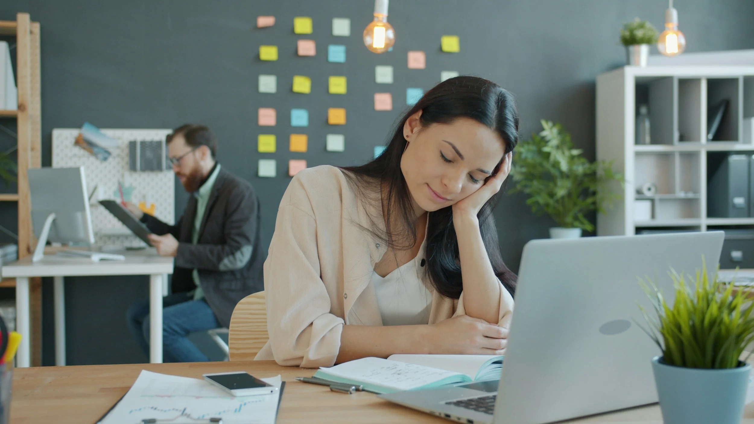 Woman at work at her desk head resting in her hand and eyes closed, tired, sleepy,