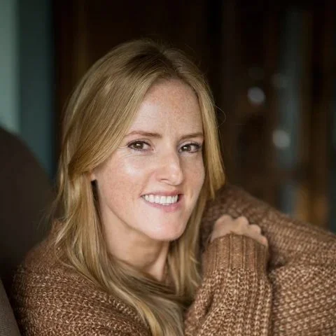 Laura sitting arms in cosy jumper smiling