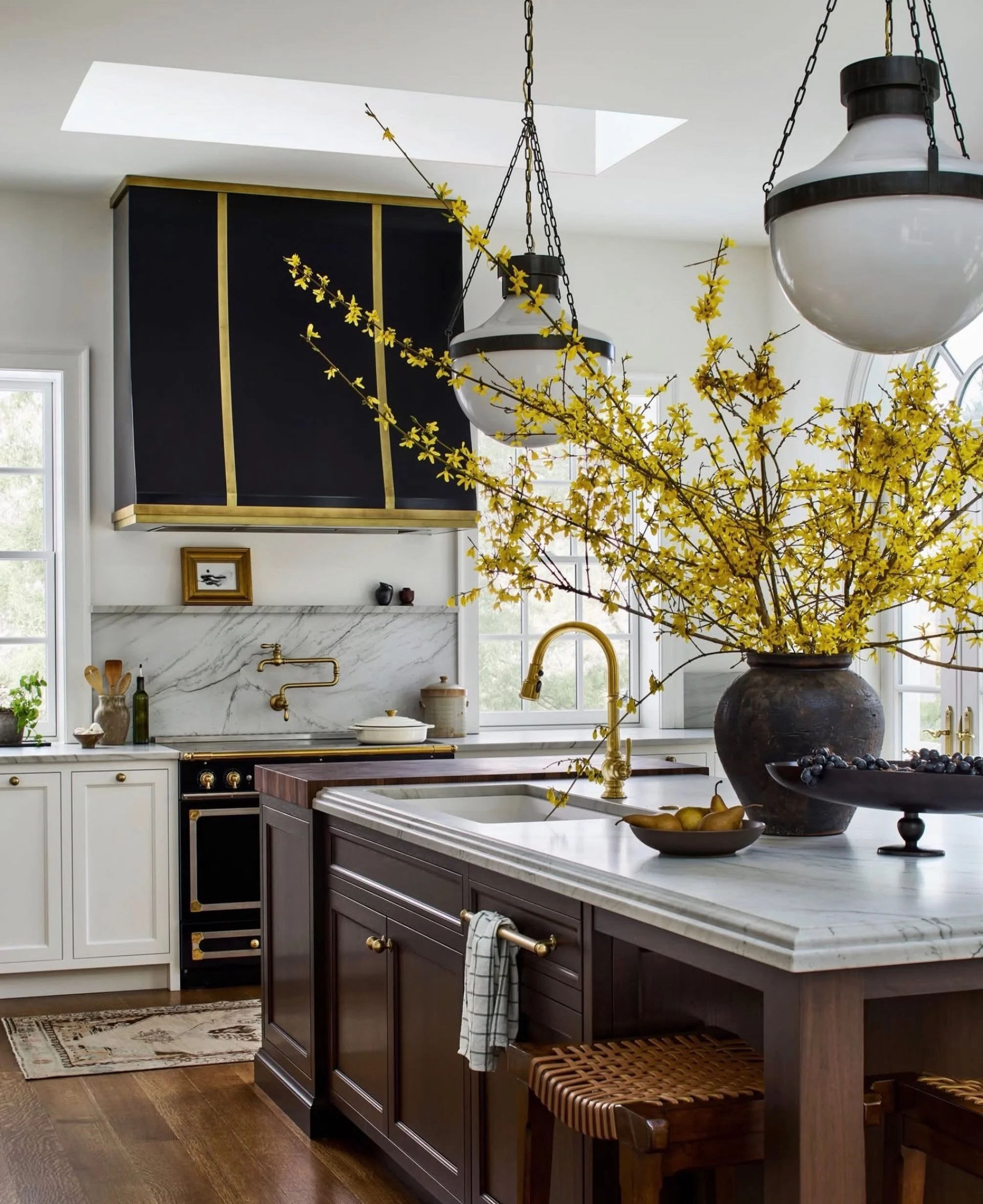 Dark wood is BACK&mdash;and I&rsquo;m here for it. 🤎 Loving this kitchen and the reappearance of dark wood in home interiors. Add-in this kitchen&rsquo;s elevated detailing (the range+hood with brass accents and those great, globe pendants (!!) &hel