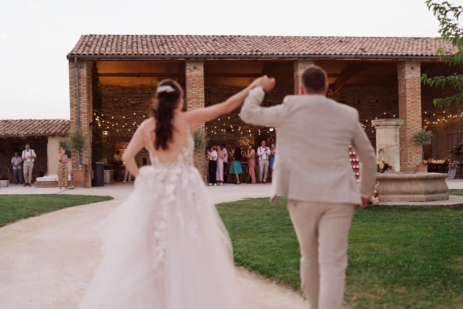Mariés entrant dans la soirée de mariage sous guirlandes lumineuses en Provence.