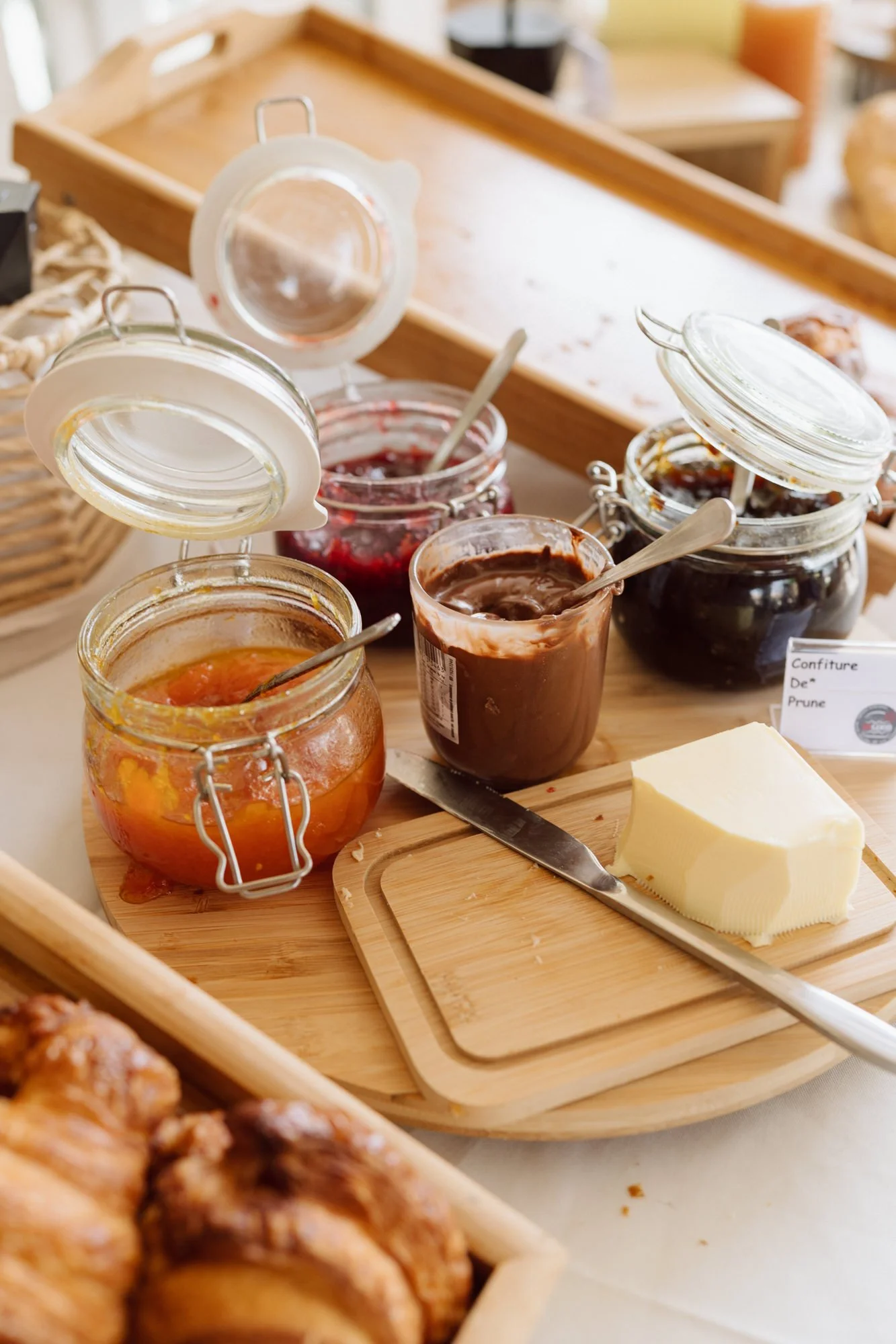 Buffet de brunch de mariage avec confitures artisanales, pâte à tartiner, beurre et viennoiseries sur table en bois