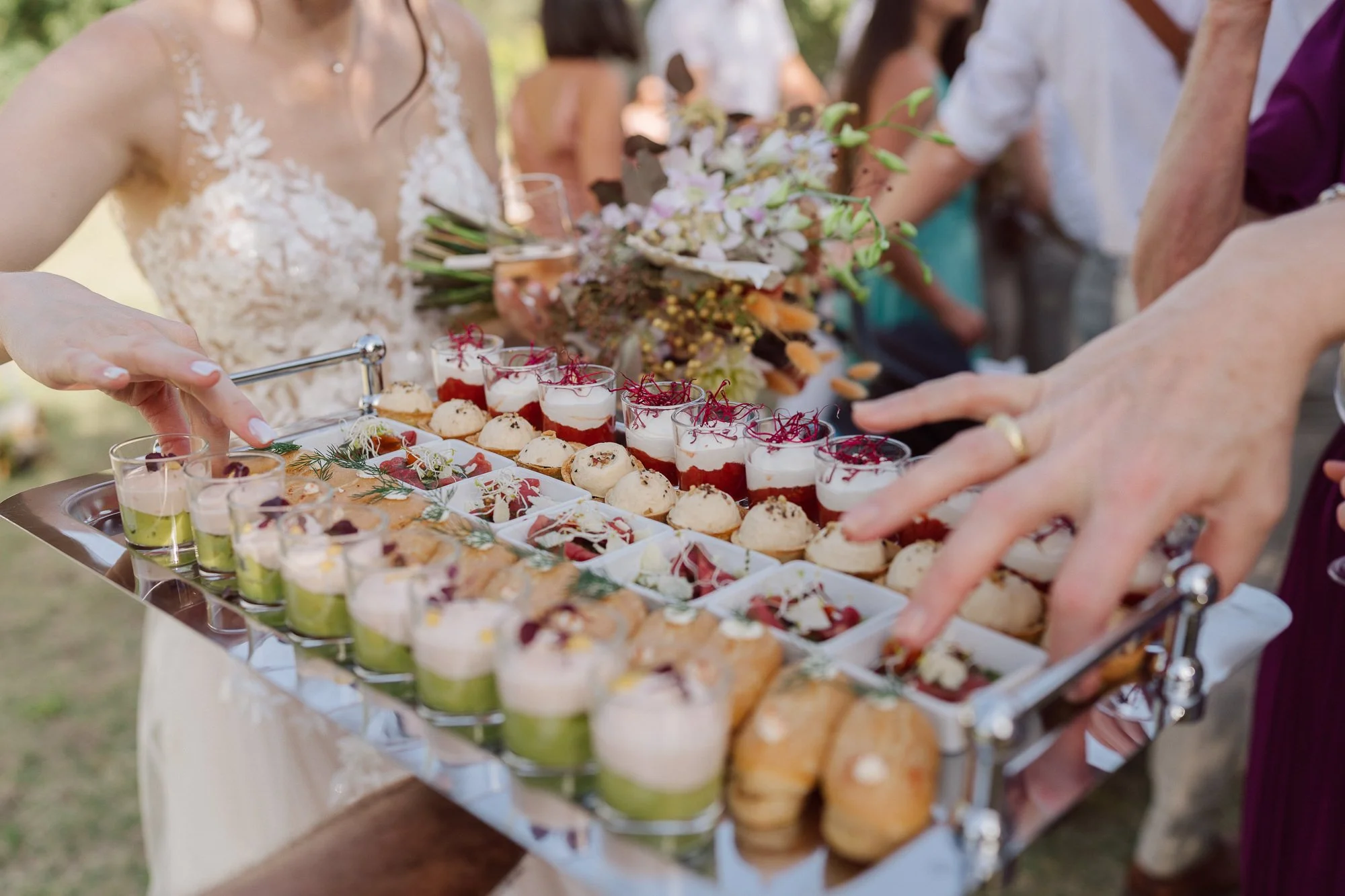 Plateau de pièces cocktail gastronomiques servi lors d’un mariage au Domaine de Sarson en Provence, invités en arrière-plan pendant le vin d’honneur.