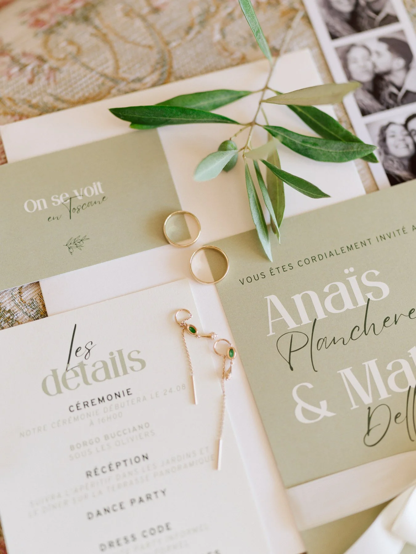 Un flatlay raffiné mettant en avant le faire-part de mariage d'Anaïs Plancherel et Matteo Dell'Orefice. Les tons doux et naturels de la papeterie se marient harmonieusement avec des éléments tels que des feuilles d'olivier, des alliances dorées, et u