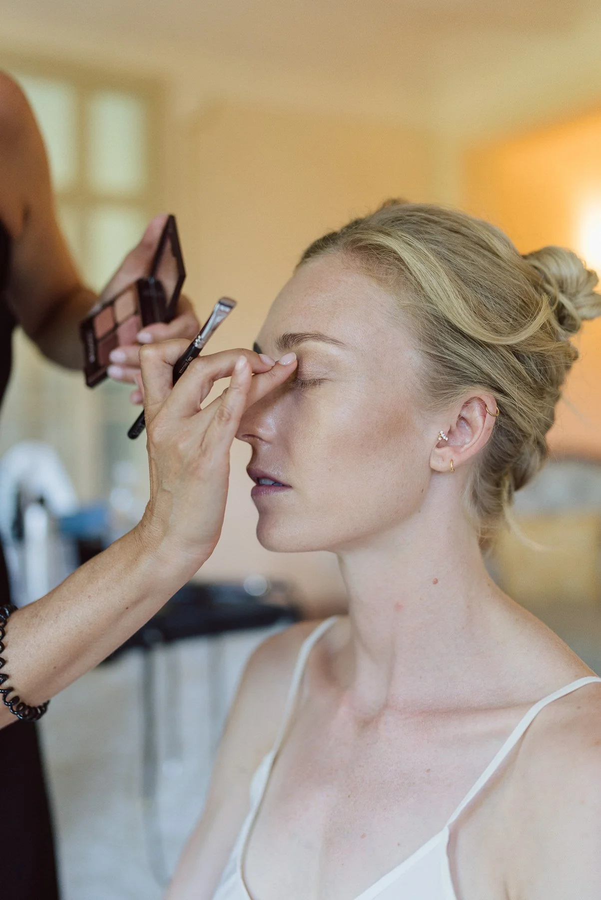 Maquilleuse appliquant le maquillage de la mariée pendant les préparatifs d’un mariage en Toscane, Italie