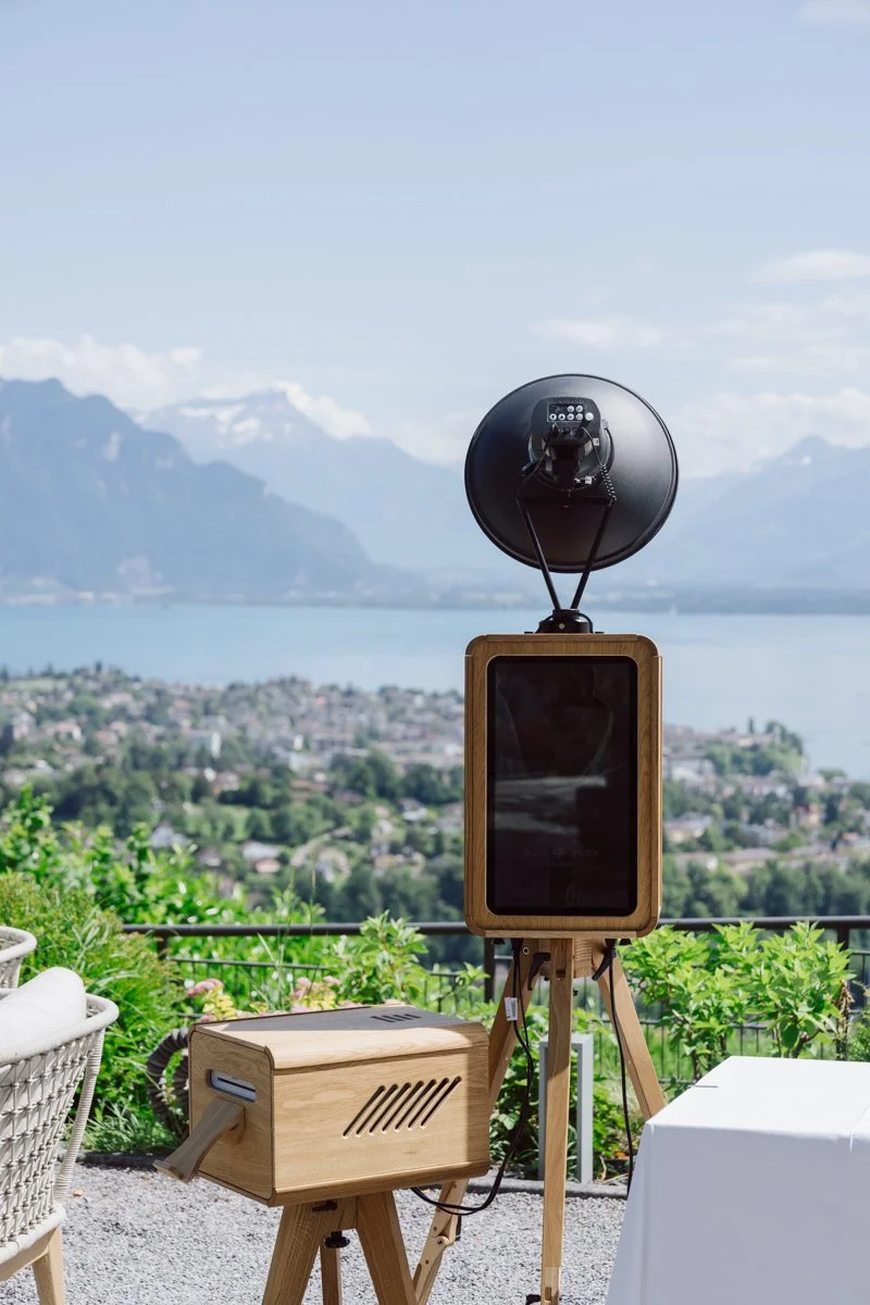 Photobooth en bois installé pour un mariage avec une magnifique vue sur le lac Léman et les Alpes suisses.